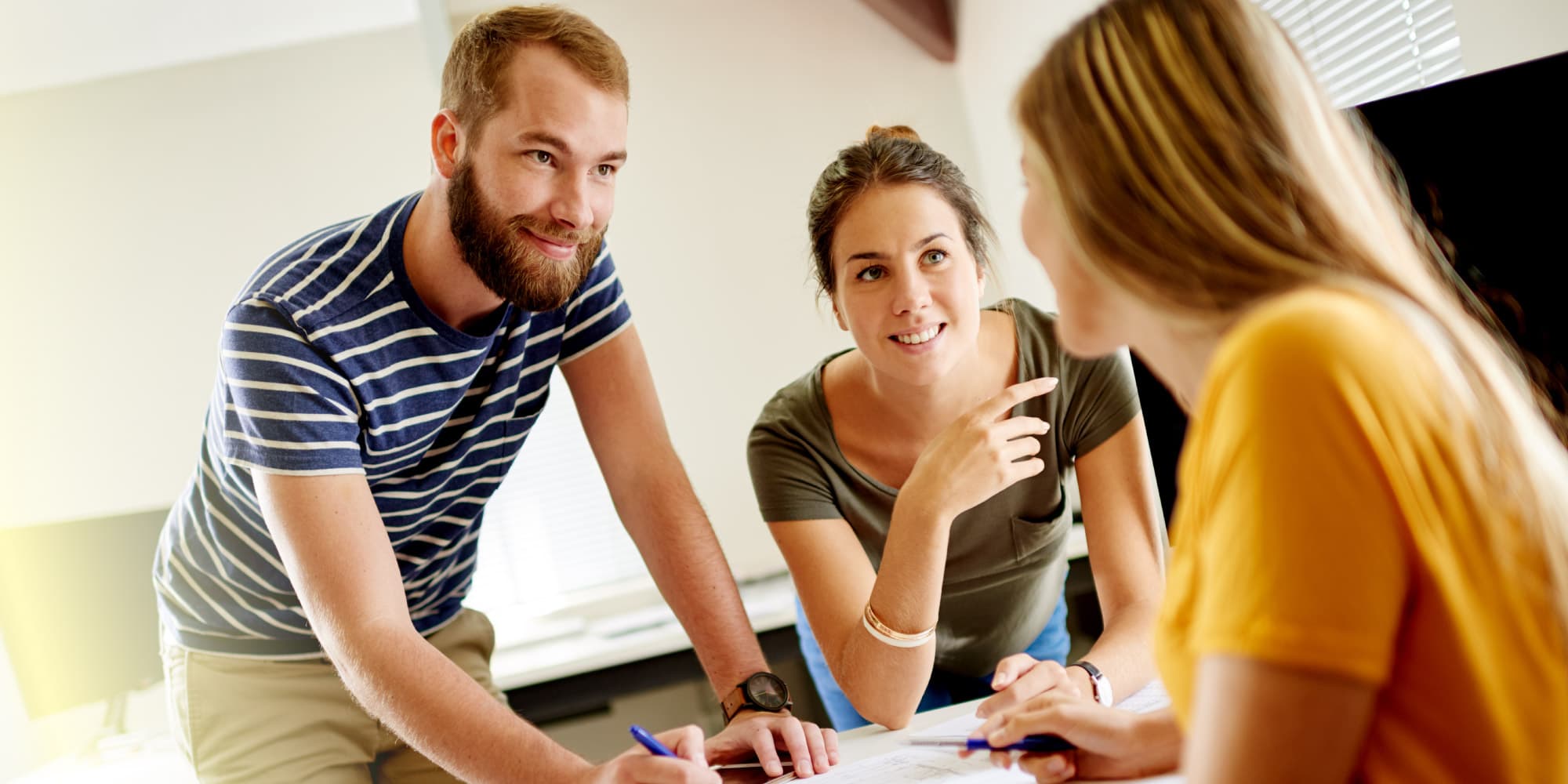 iStart-header Drie personen bespreken ideeën rond een tafel tijdens een start-upcoachsessie