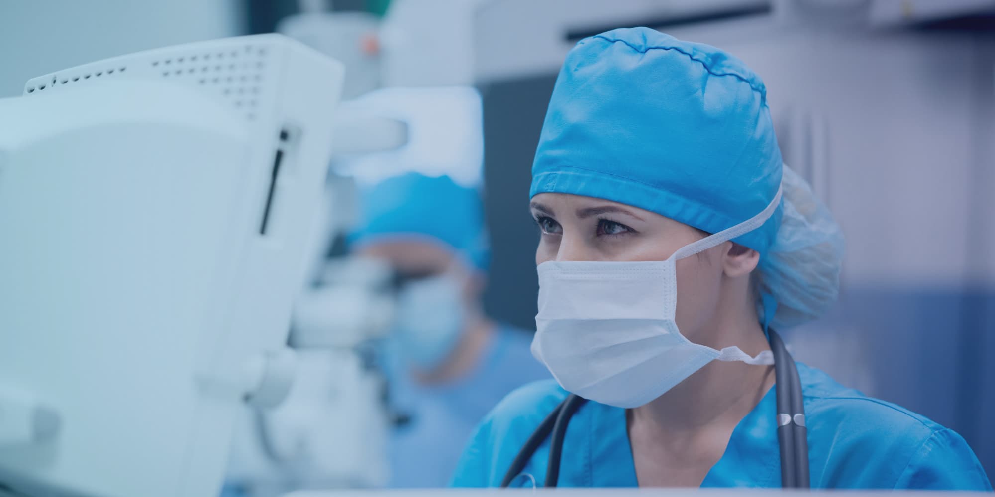 masked medical researcher working in lab Masked medical researcher in blue scrubs working beside lab equipment