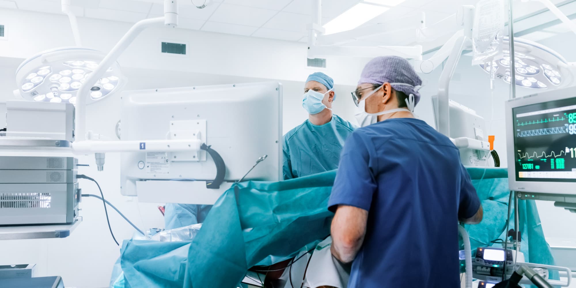 Surgical-imaging Surgeons working in a bright operating room beside patient monitors and surgical lights