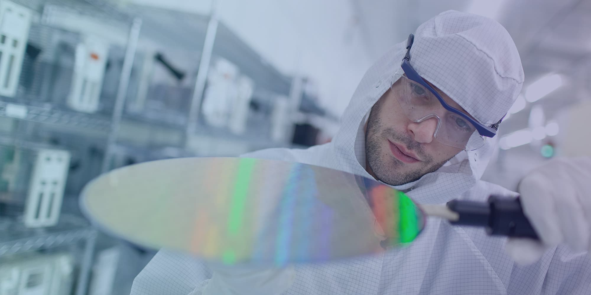 ASIC-fabrication_0 Researcher in cleanroom gear inspecting a silicon wafer in a semiconductor lab