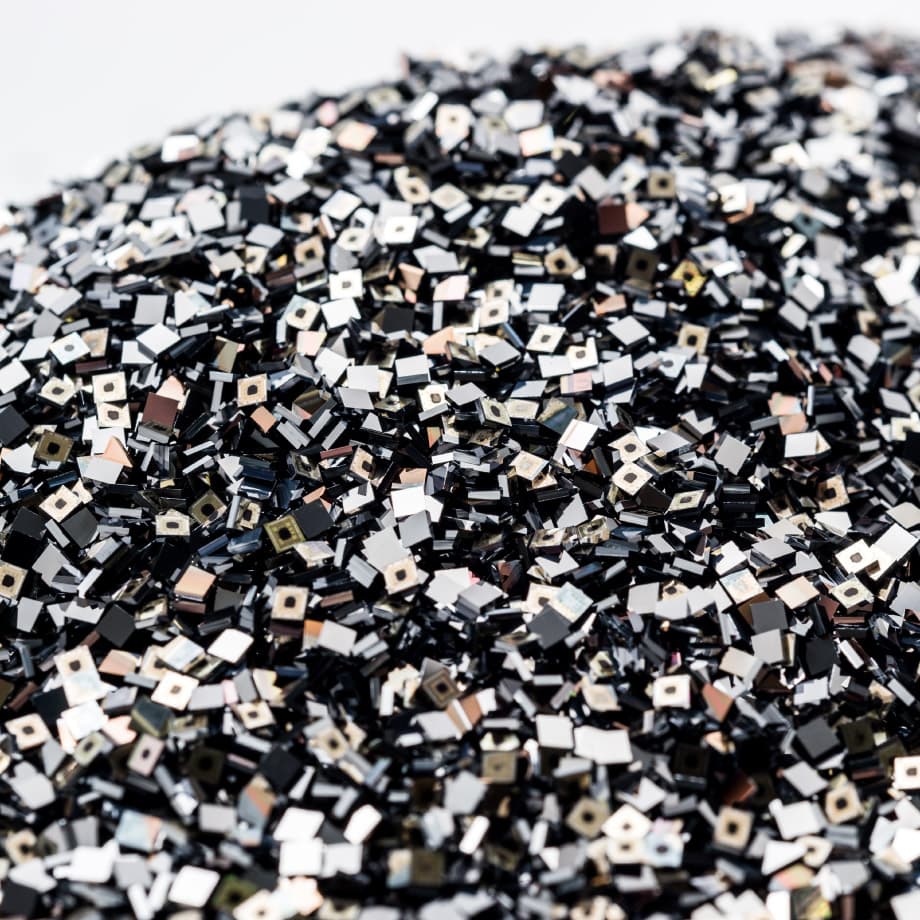Volume-production-with-a-tailored-supply-chain- Pile of small square semiconductor chips or dies, many with metallic surfaces and dark edges