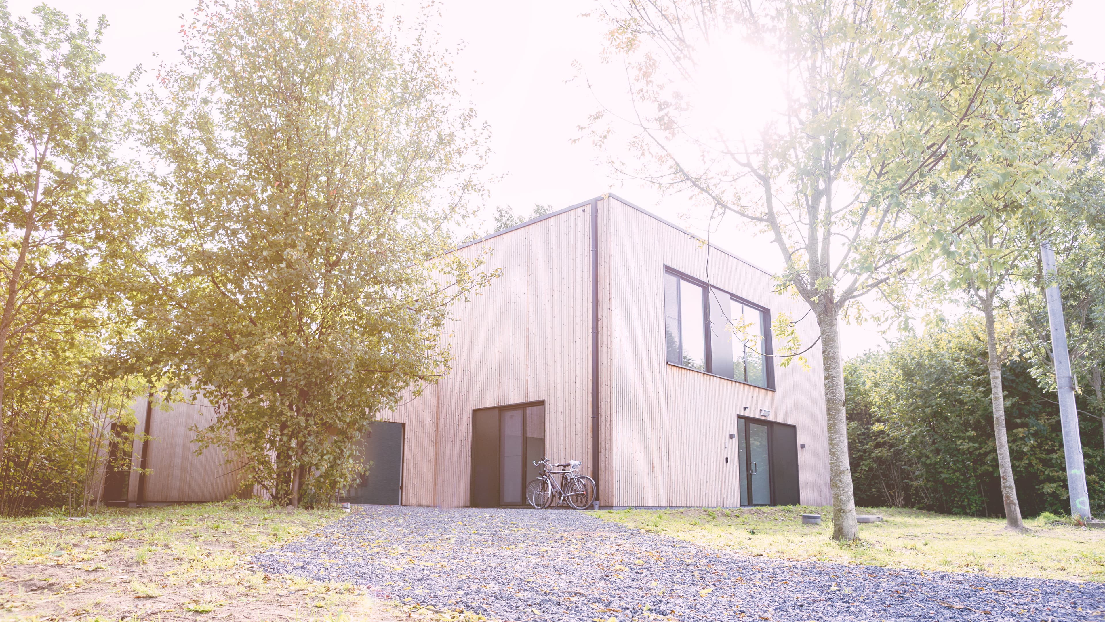 wooden residential test house with bicycles outside Wooden residential test house surrounded by trees, with bicycles parked outside.