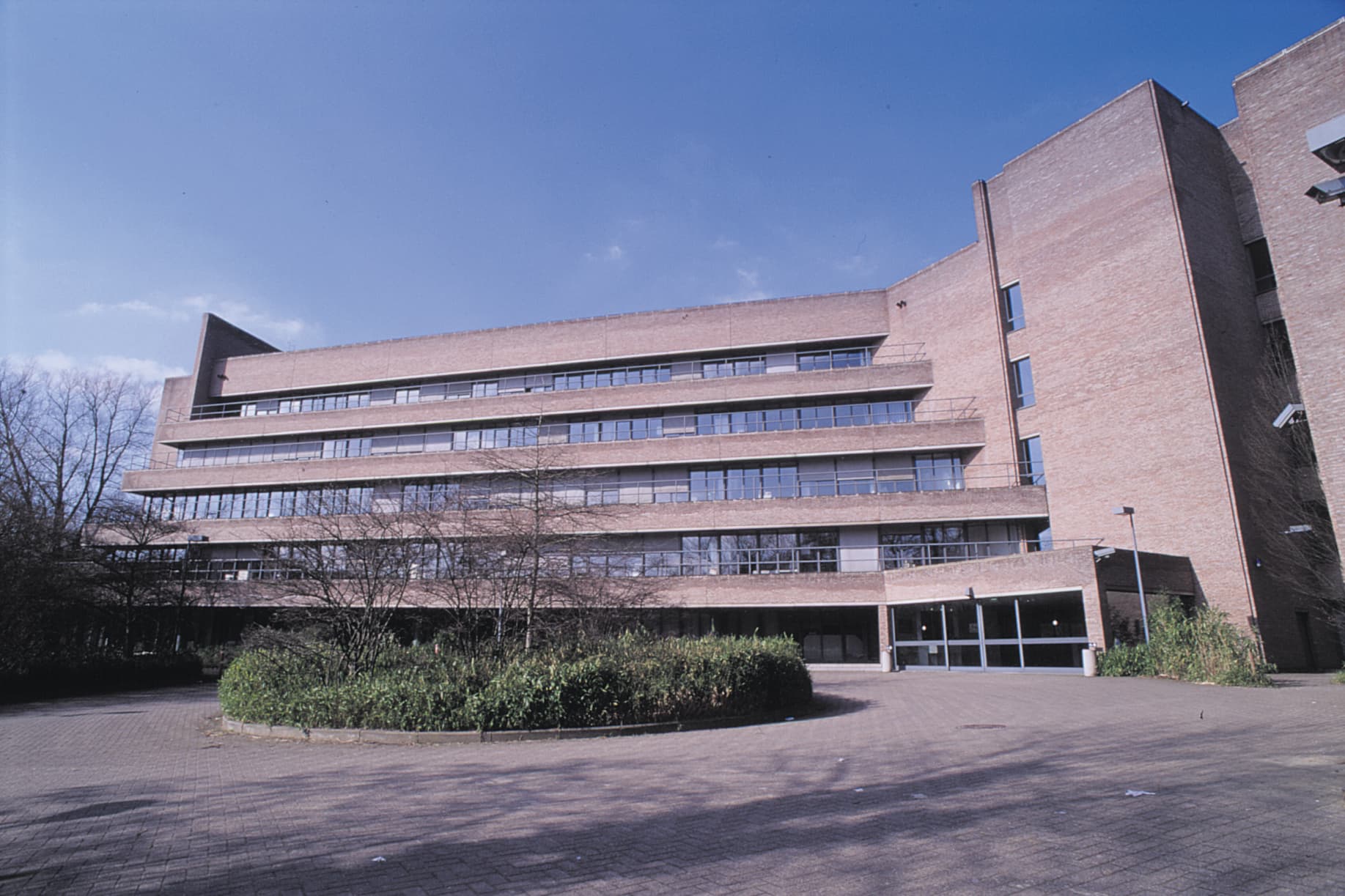 01-building The first imec building, a brick office block with a wide courtyard and blue sky.
