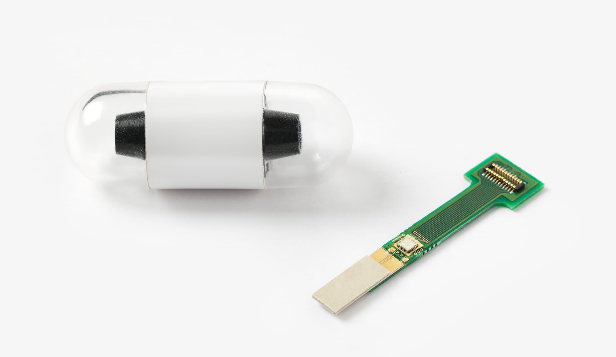 011_header_1 Electronic pill capsule beside a tiny wireless transceiver circuit board