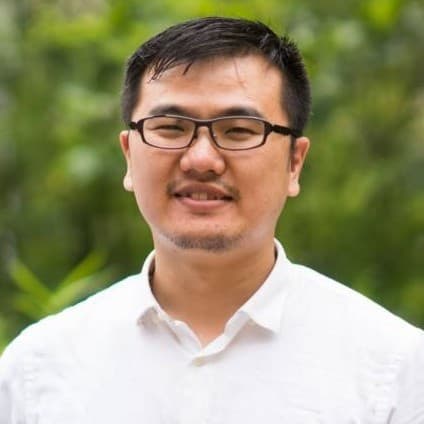 portrait of research and development manager Tung-Huei Ke, research and development manager at imec, wearing glasses and a white shirt against a blurred green background.