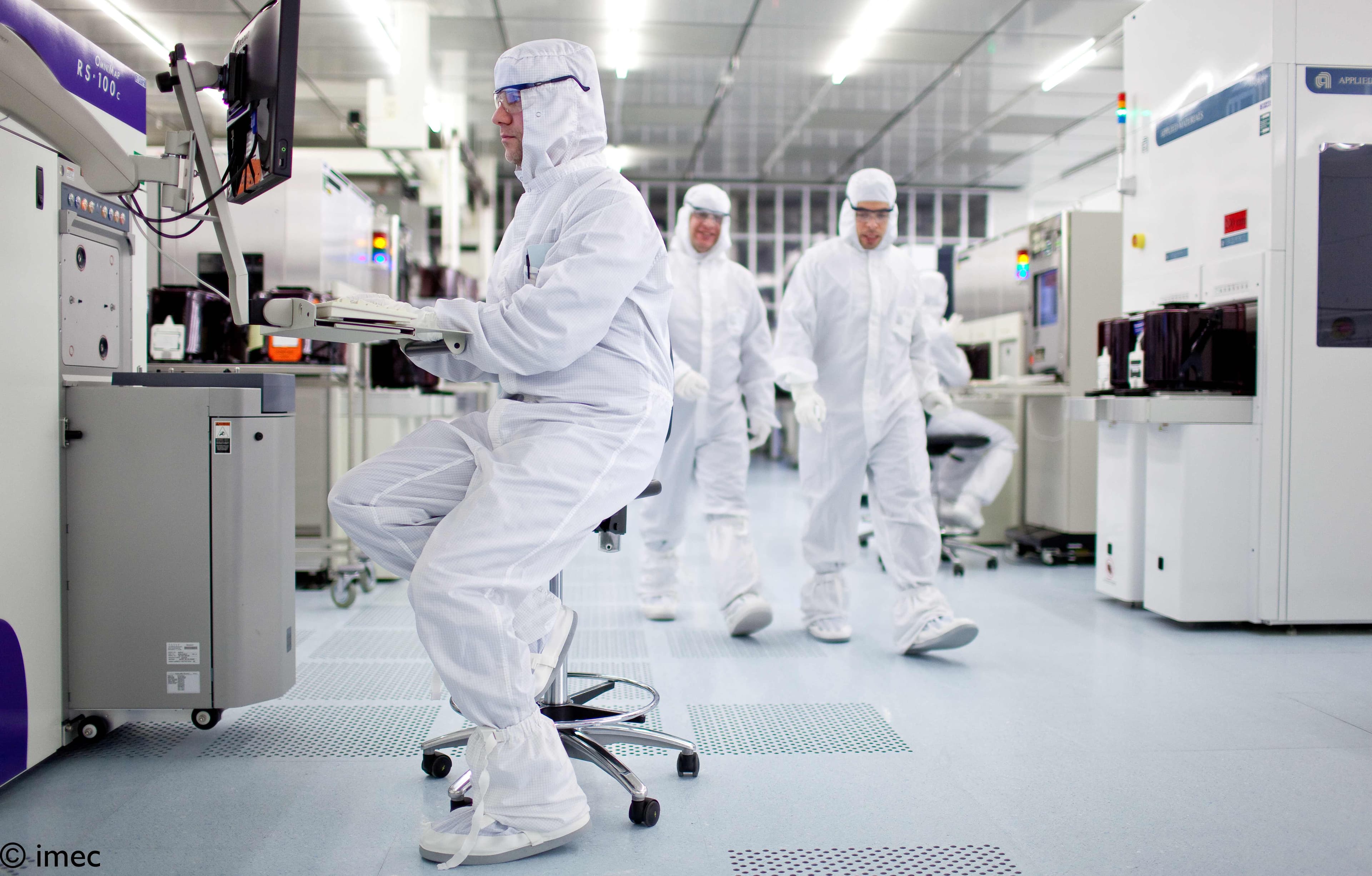 169-A-look-inside-imec%27s-300mm-cleanroom-2022%20%281%29 Researchers in cleanroom suits working among semiconductor equipment in a cleanroom