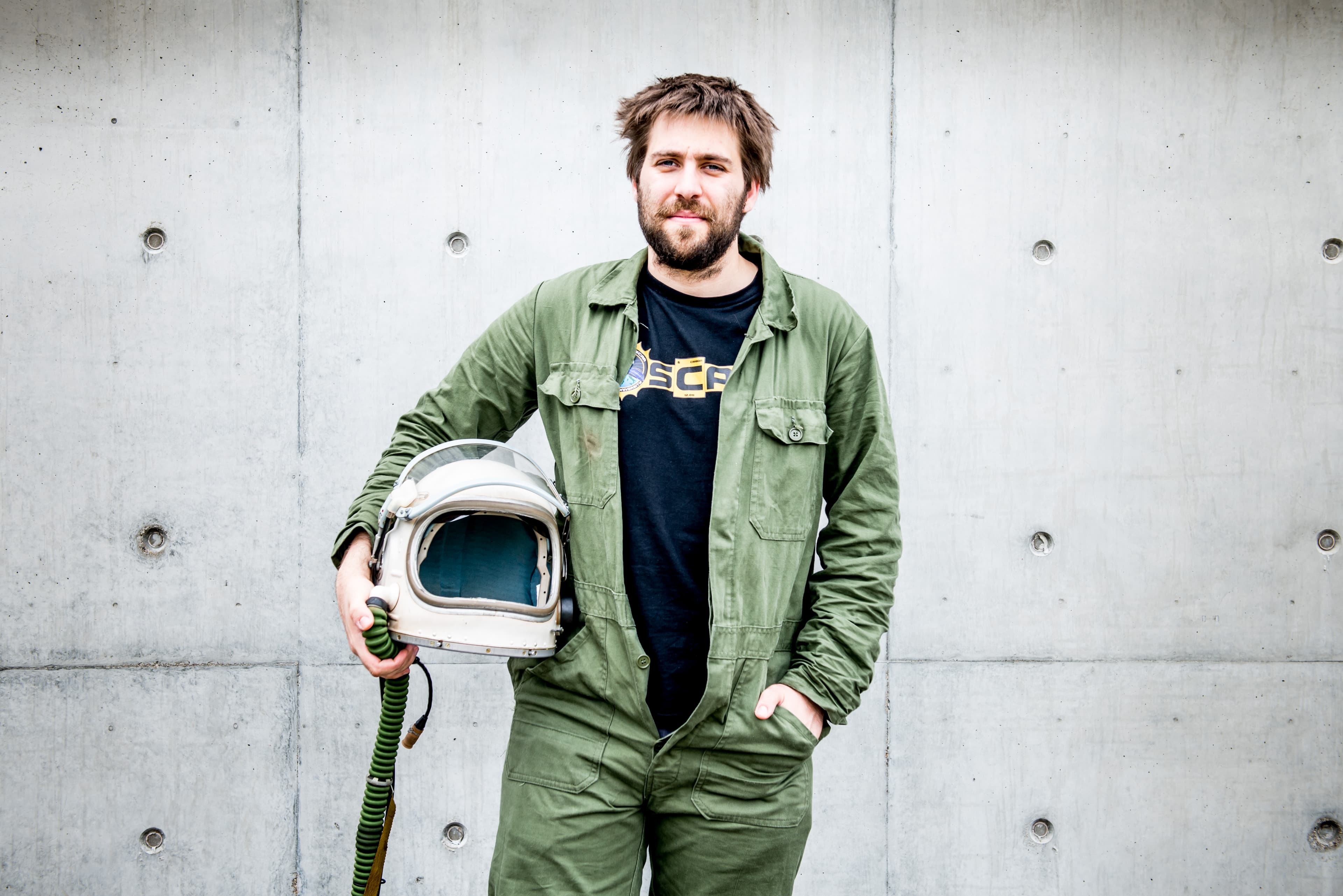 2_JaroslavHruby Jaroslav Hruby standing against a concrete wall, holding a space helmet under his arm