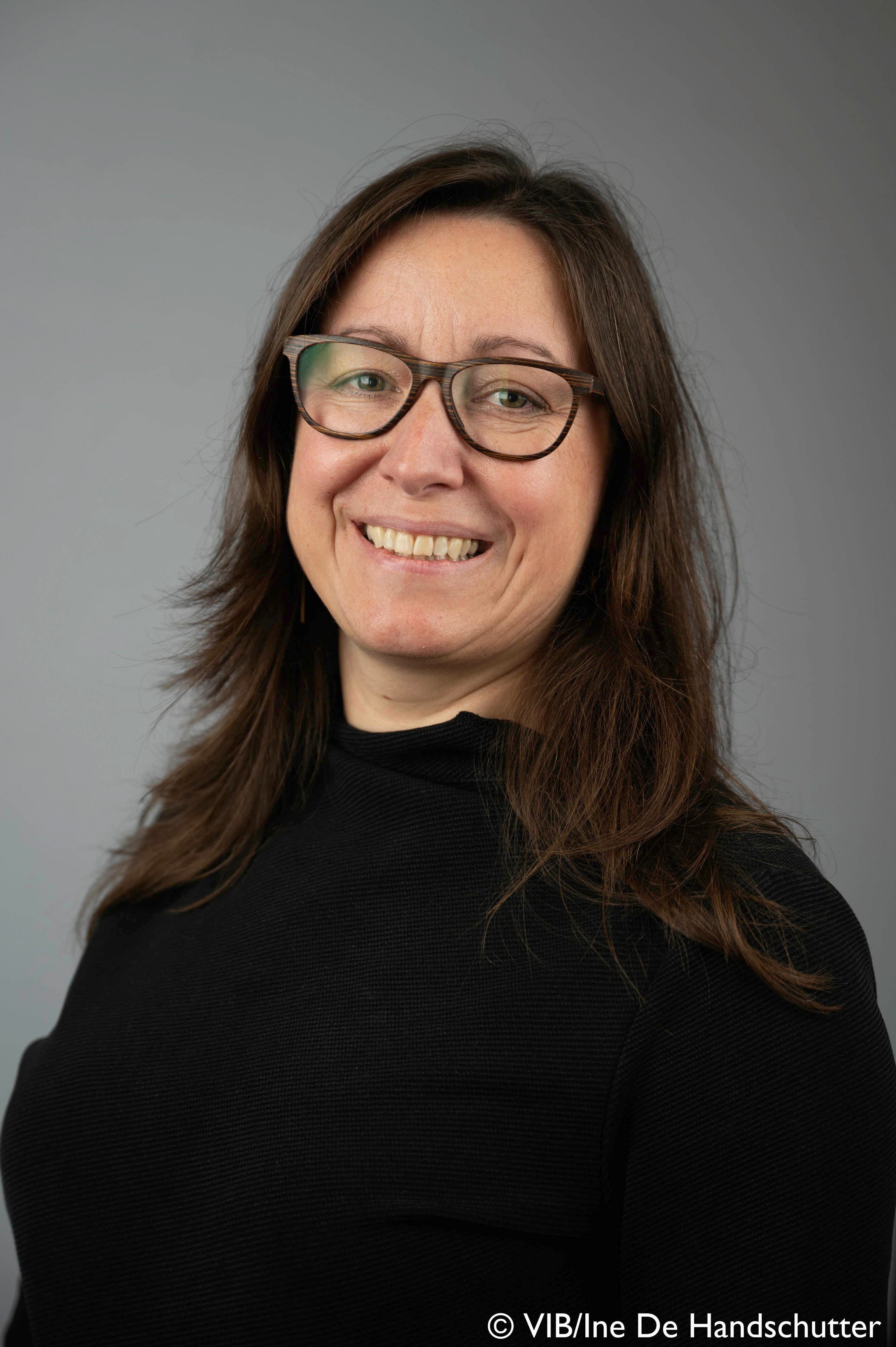 20221017-vib-IneDehandschutter-highres-19-Saskia%20Lippens-Bioimaging%20Core%20Ghent-5 Portret van Saskia Lippens, glimlachend tegen een effen grijze achtergrond