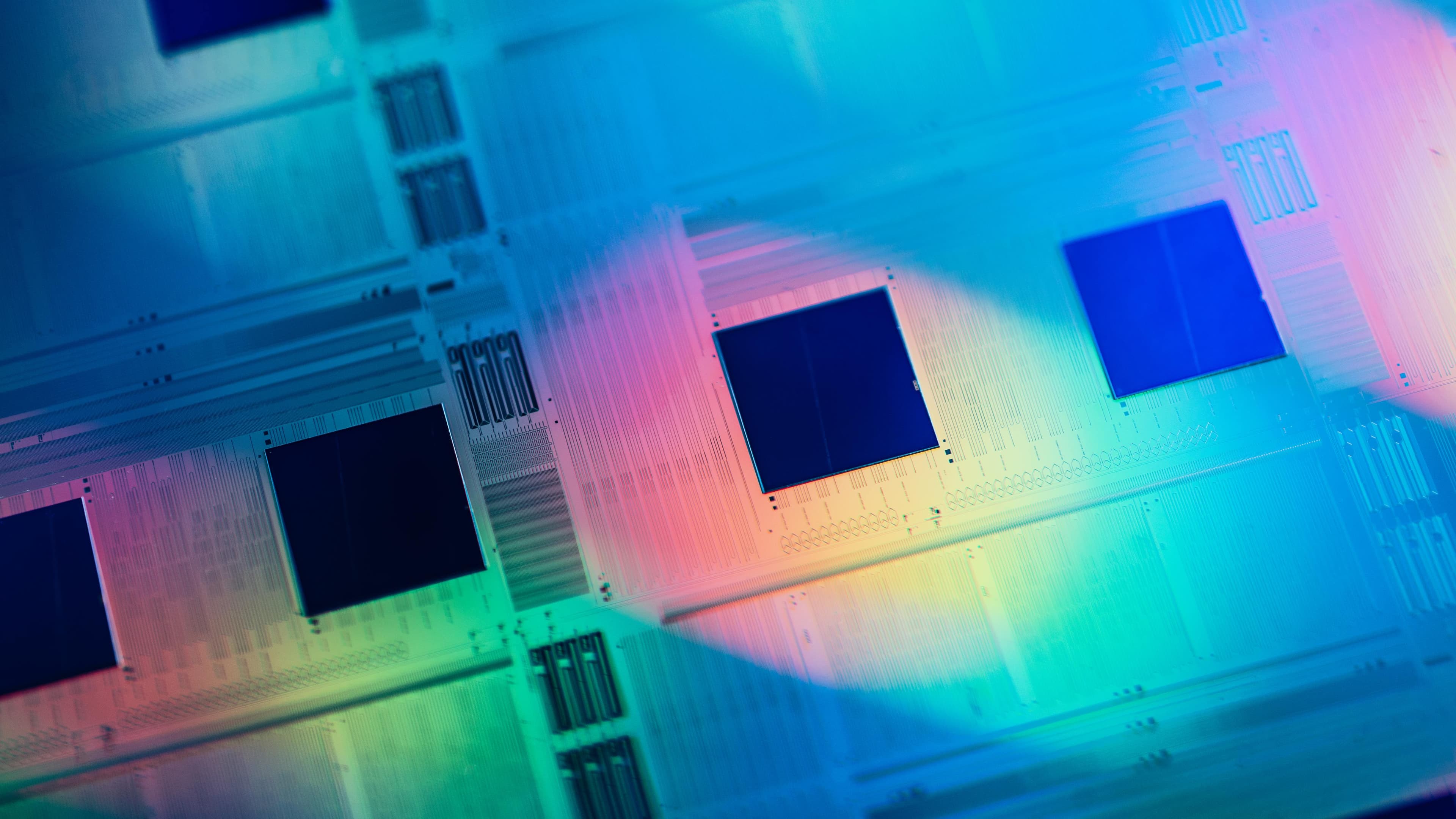 2024_Si%20photonics%20wafer%20with%20bonded%20photonic%20ICs Fotonische wafer met gebonden chipstructuren in regenbooglicht
