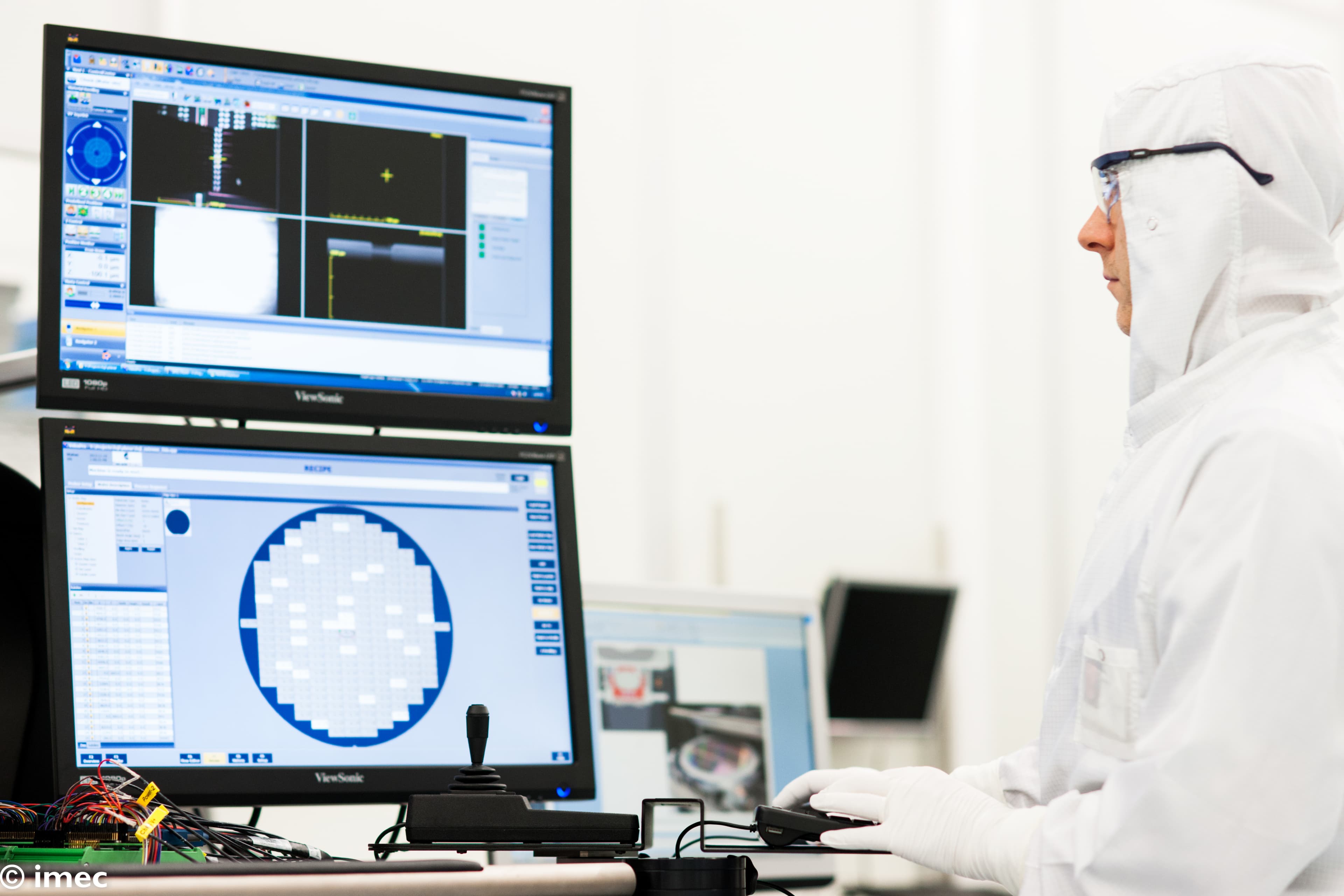 272-working-in-imec%27s-300mm-cleanroom-2022_scale_70_ppi_300_quality_100 Cleanroom technician in white suit monitoring wafer inspection screens