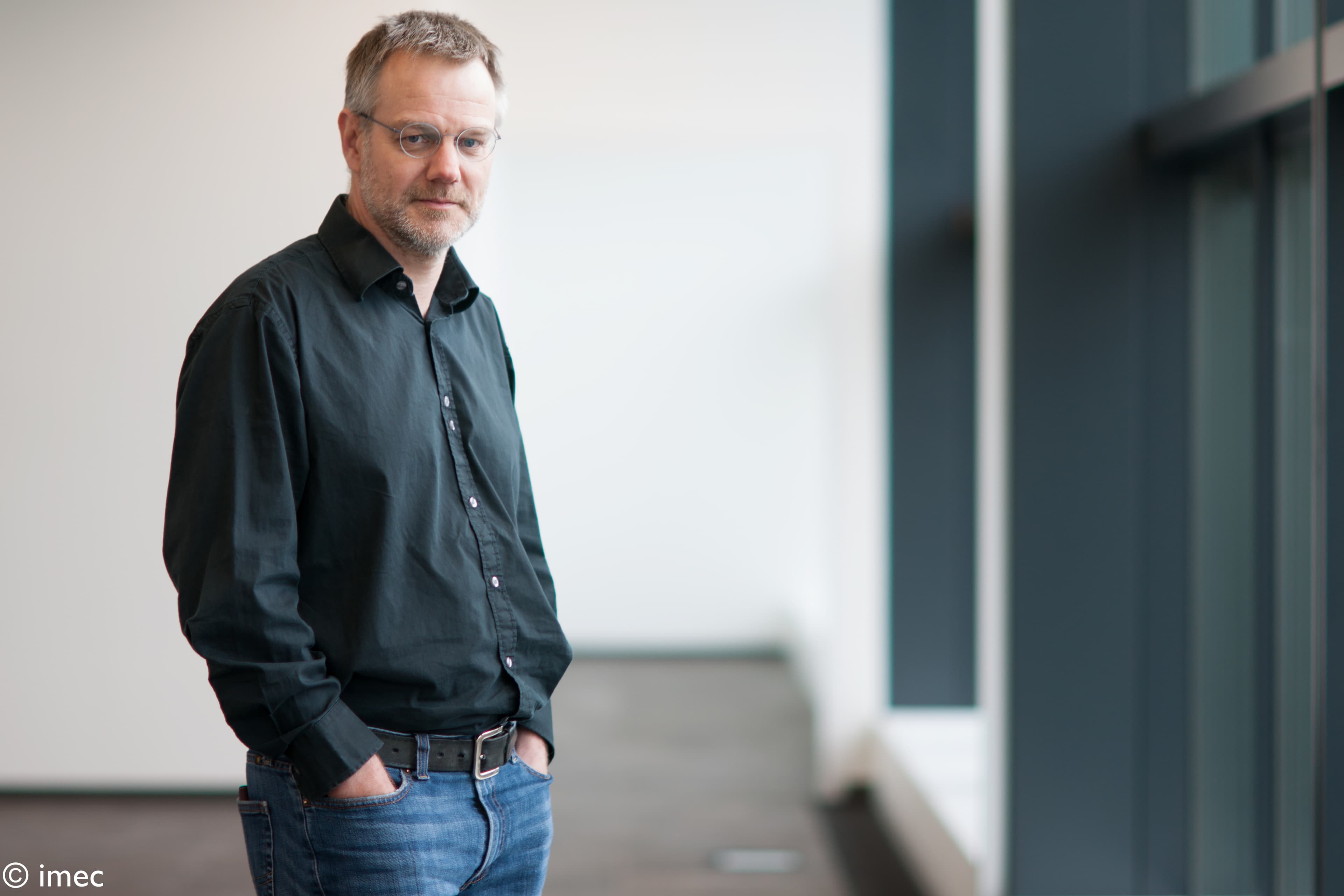 28793315721_ee41bb027d_o_1 Portrait of Wilfried Verachtert standing indoors in a black shirt and glasses