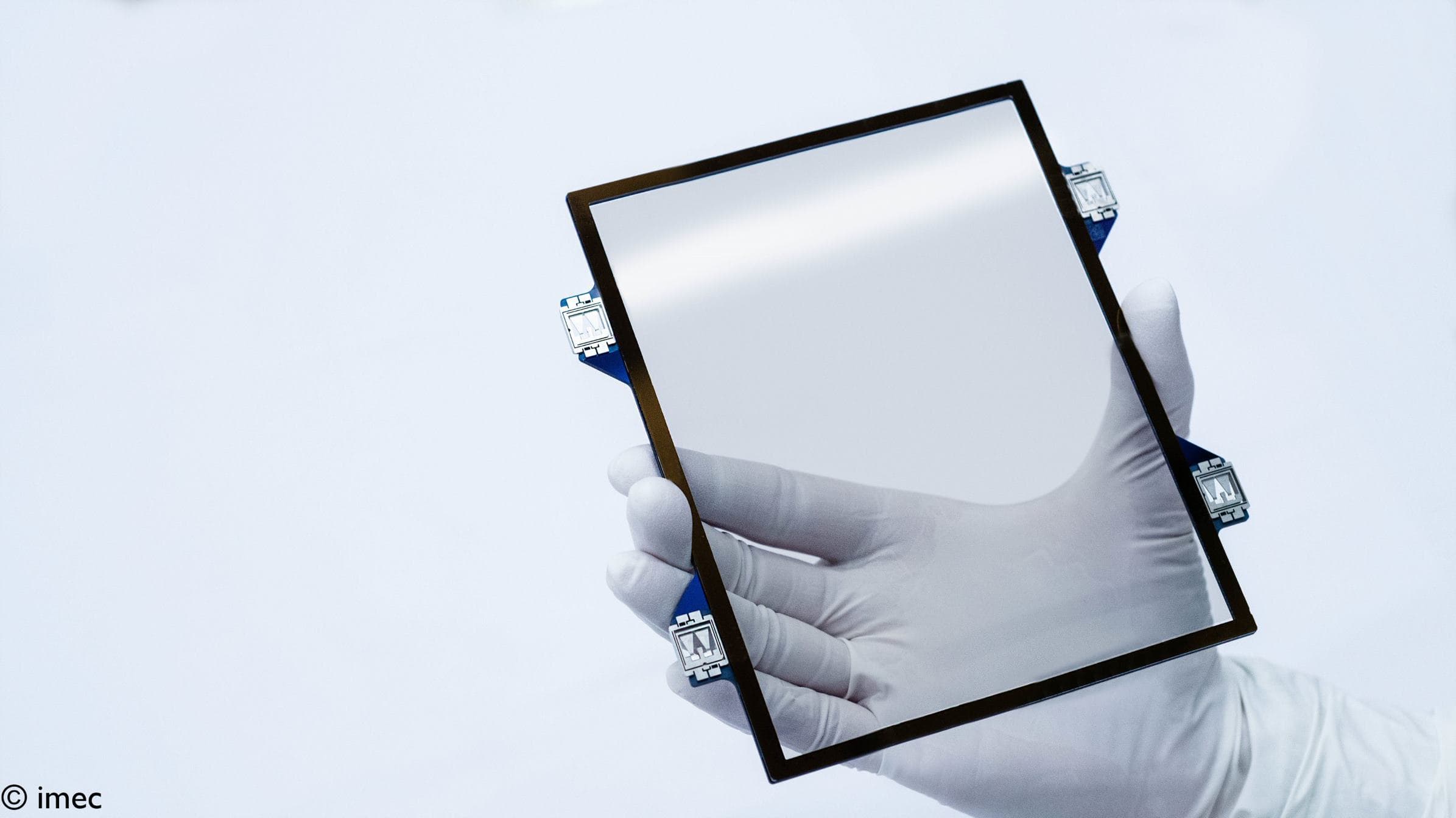 Hand holding semiconductor pellicle frame Gloved hand holding a square semiconductor pellicle frame against a white background