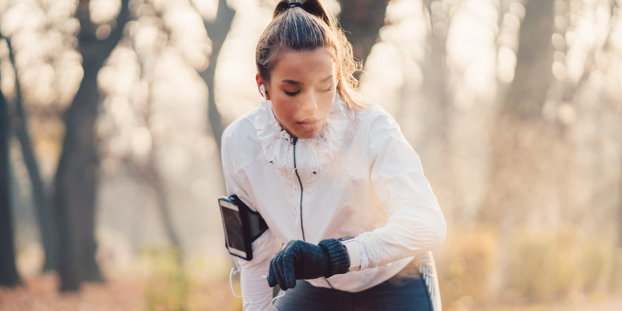 3_radar-voor-healthcaretoepassingen_1 Runner checking a wrist device outdoors while listening with earbuds