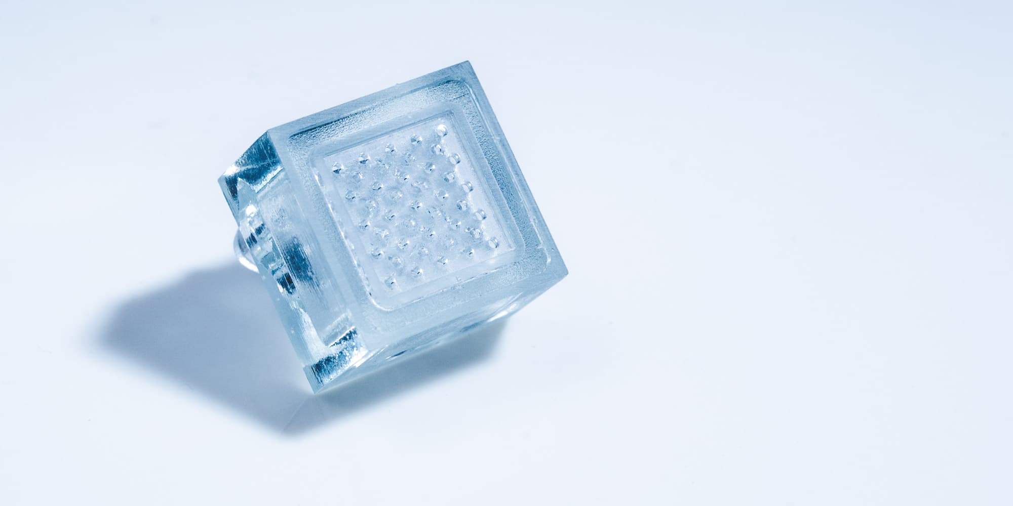 3D-Printed-Fluidic--Cooler001_1 Transparent 3D-printed fluidic cooler block with internal channels on a white background
