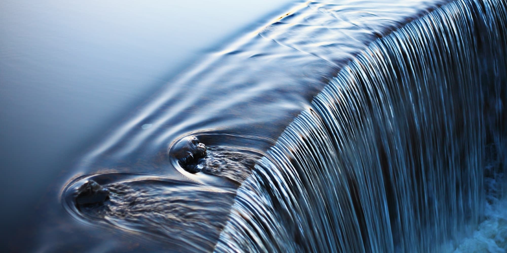 Close-up of water flowing over curved edge forming ripples Close-up of water flowing over a curved edge, forming ripples and streaks.
