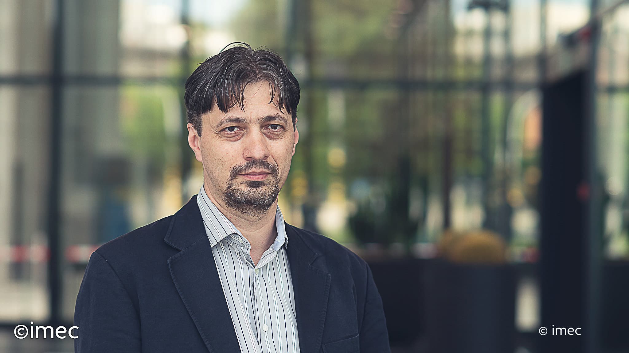 Portrait of man in blazer indoors Portrait of Bogdan Govoreanu in a blazer, standing indoors with a softly blurred glass background.