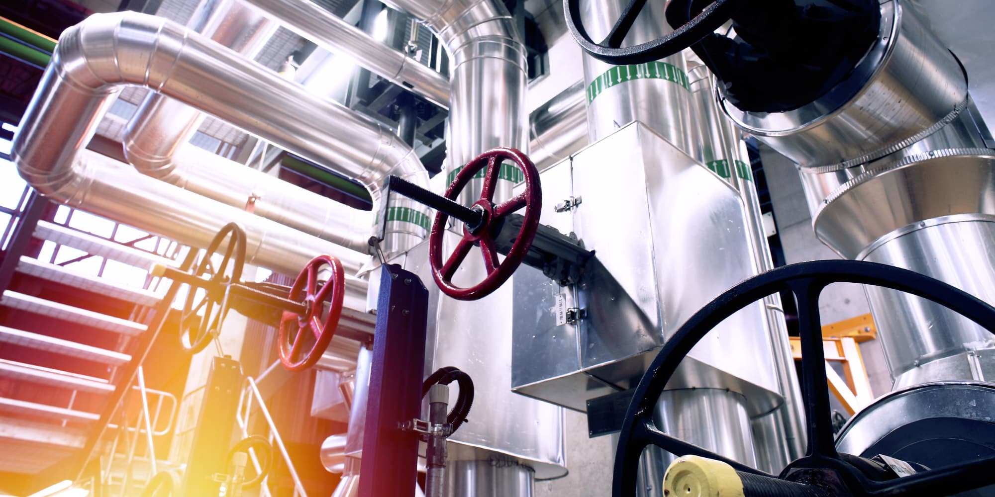 6.-modular-industrial-iot-platform-for-the-process-industry_1 Industrial piping and large valve wheels in a process plant