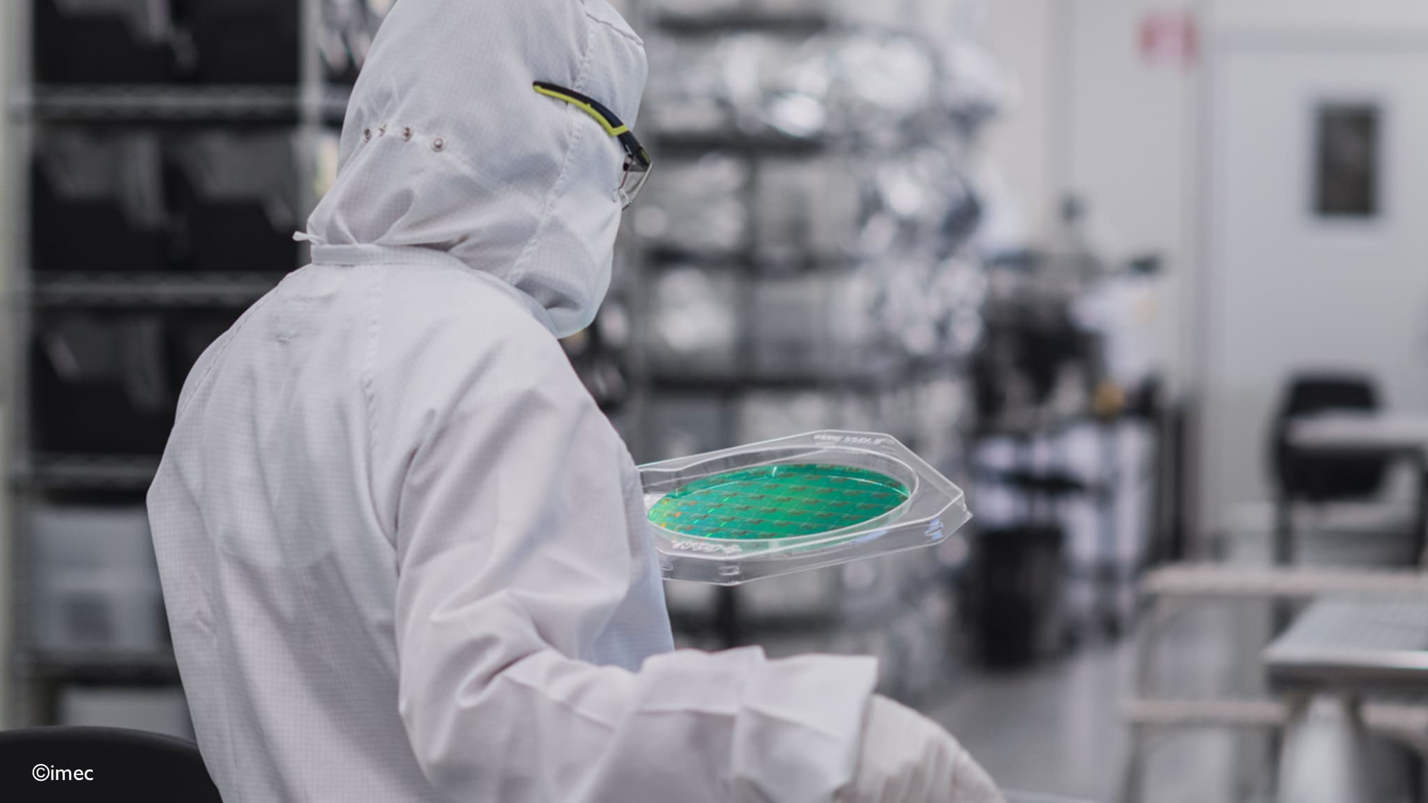 A-look-inside-imec%27s-cleanroom-2021 Cleanroom worker in protective suit holding a semiconductor wafer tray