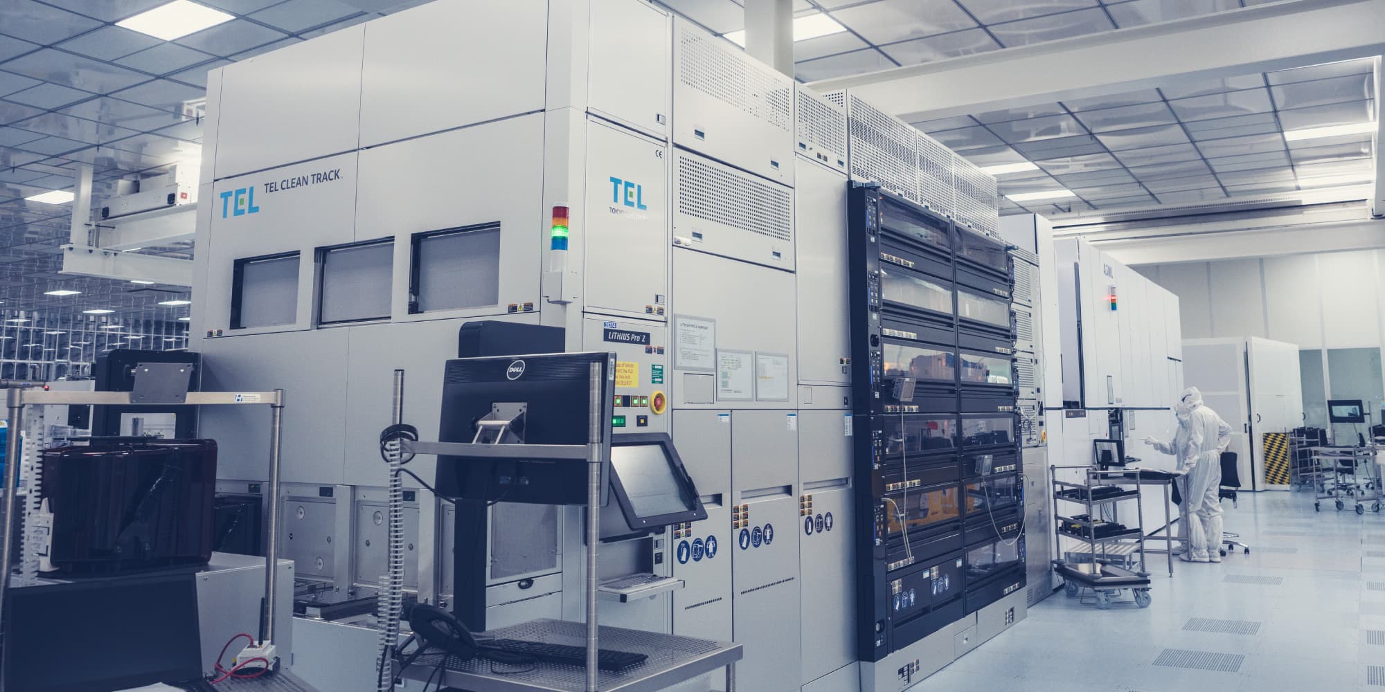 Advanced-patterning-and-key-process-steps Cleanroom with advanced semiconductor patterning equipment and two researchers in white suits