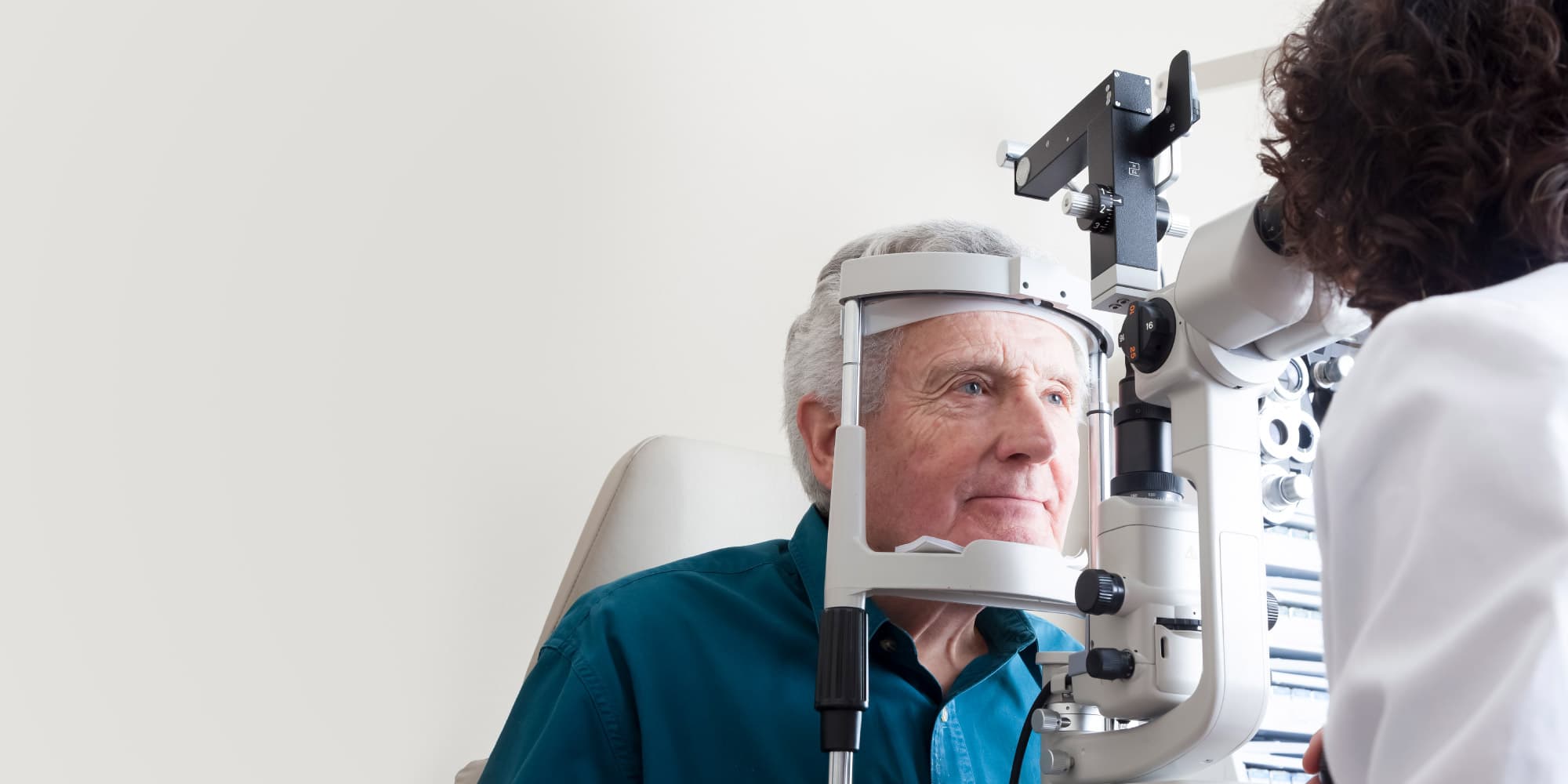 alzheimer-visual Eye examination with a patient looking into a slit lamp while a clinician adjusts the instrument