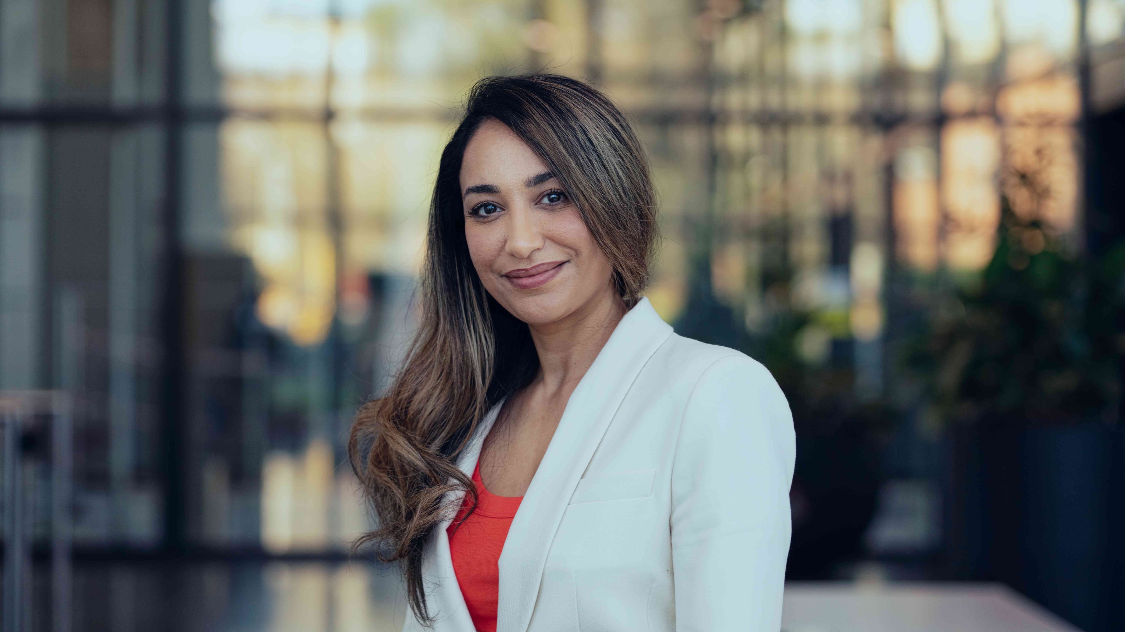 Anita%20Farokhnejad Portrait of Anita Farokhnejad in a white blazer, standing outdoors with a softly blurred background