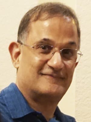 Ash%20Prabala Portrait of Ash Prabala wearing glasses and a blue shirt