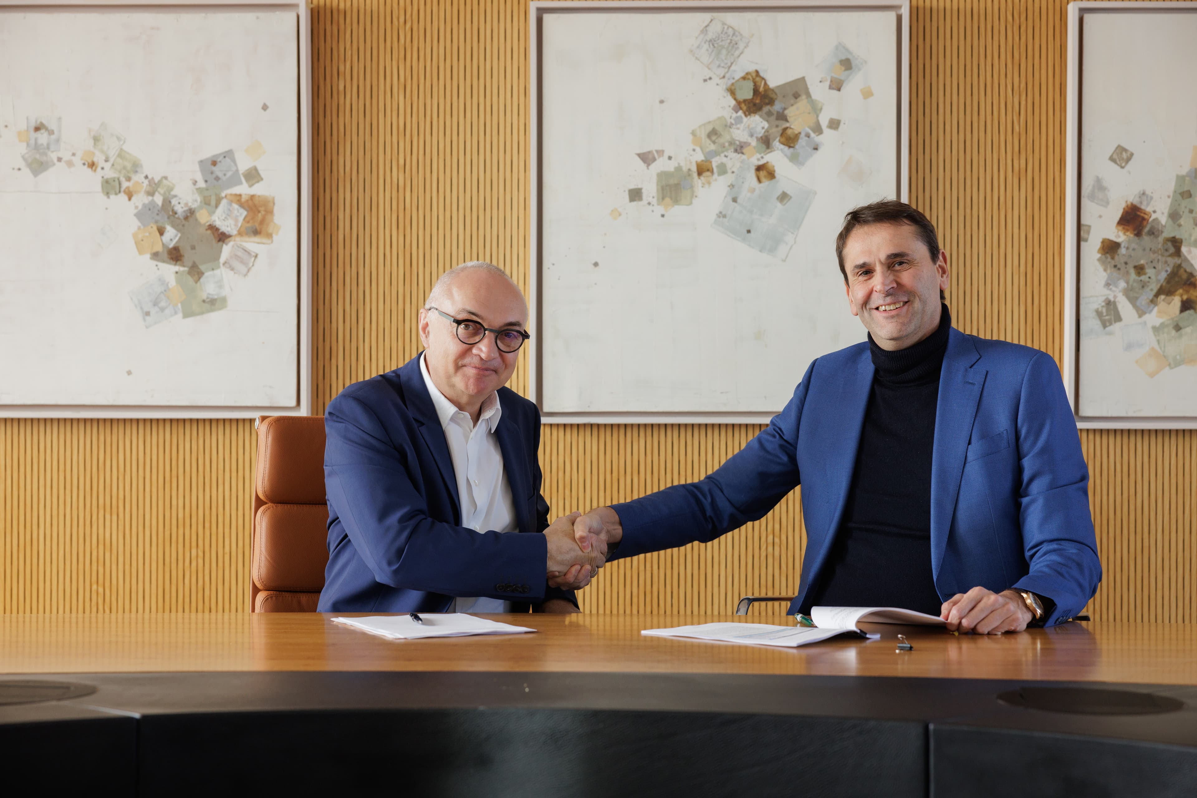 ASML_Signing_Imec_March_2025_016 Two executives shake hands over a signed agreement at a conference table.