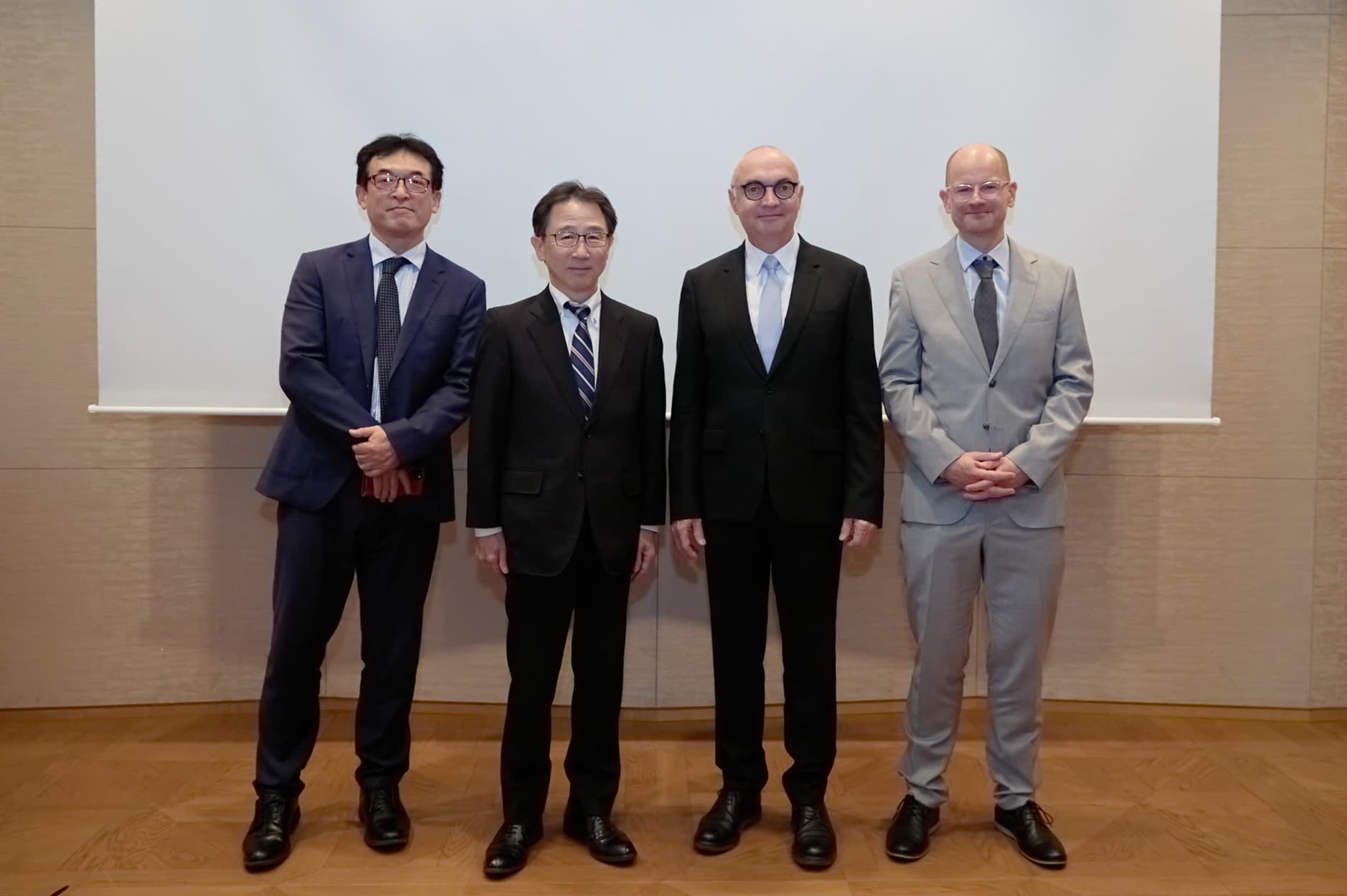 ASRA-ACP Four executives pose for a group photo in front of a presentation screen