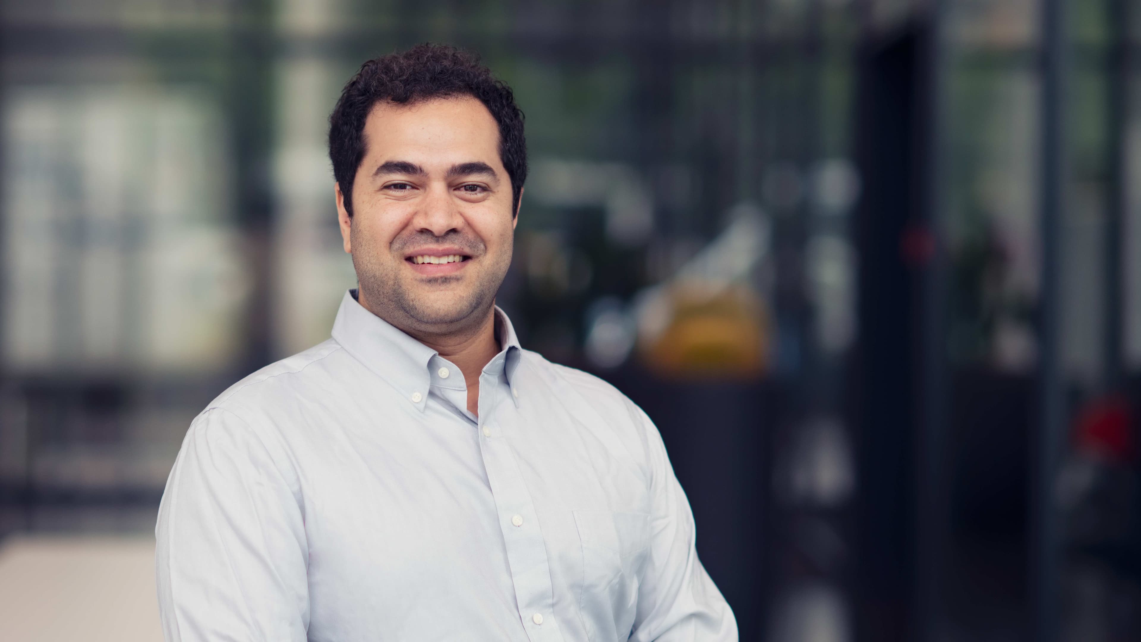 Asser%20Elsayed Portrait of Asser Elsayed smiling in a light blue shirt against a blurred laboratory background