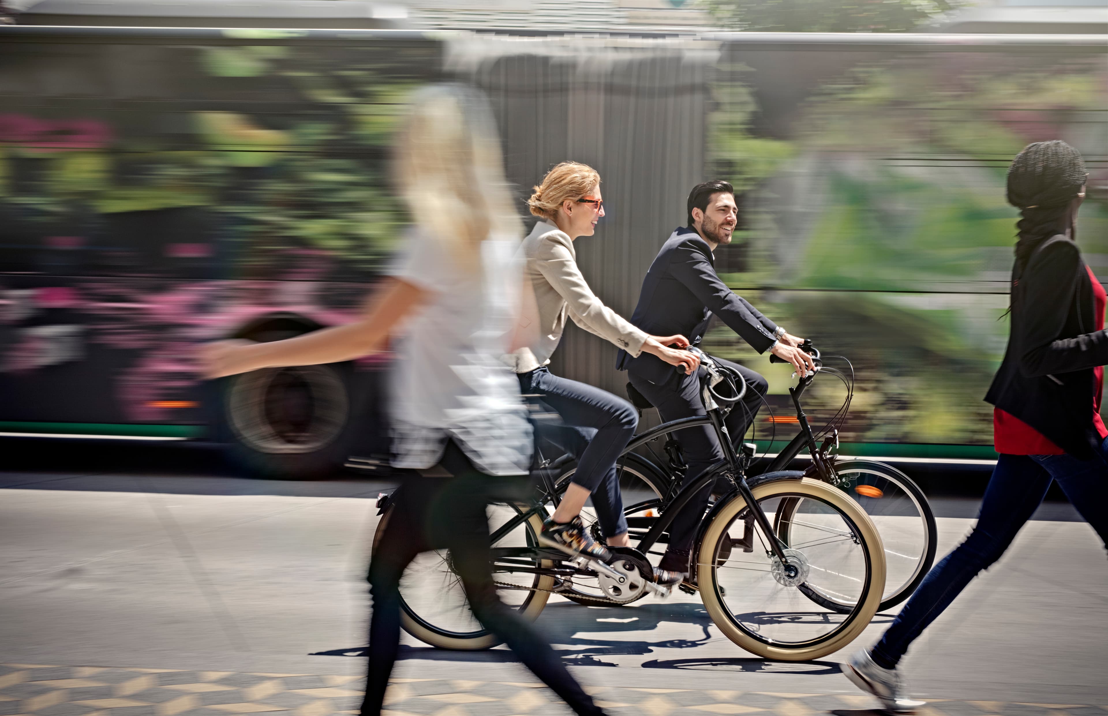 Bannerafbeelding%20mobiliteit Mensen die fietsen langs een rijdende bus op een stadsstraat, ter illustratie van stedelijke mobiliteit.
