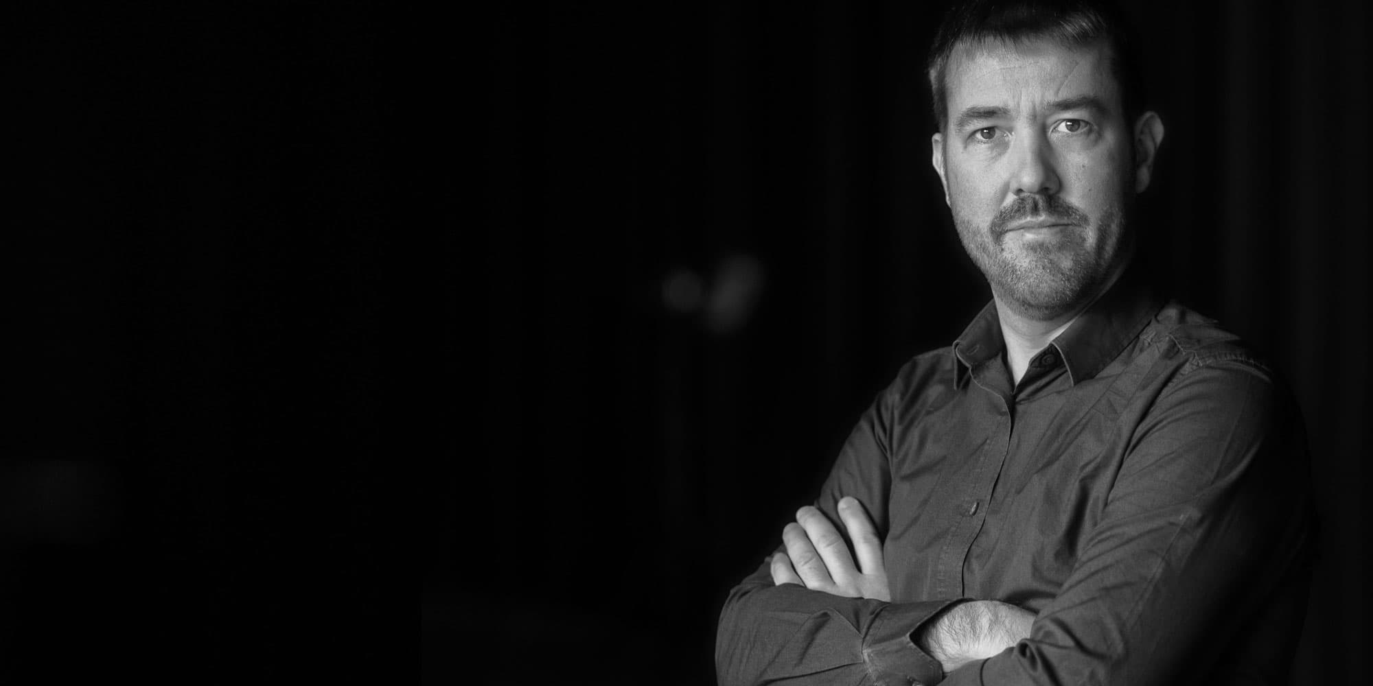 bart-onsia002magazinenew_1 Black-and-white portrait of Bart Onsia with arms crossed against a dark background