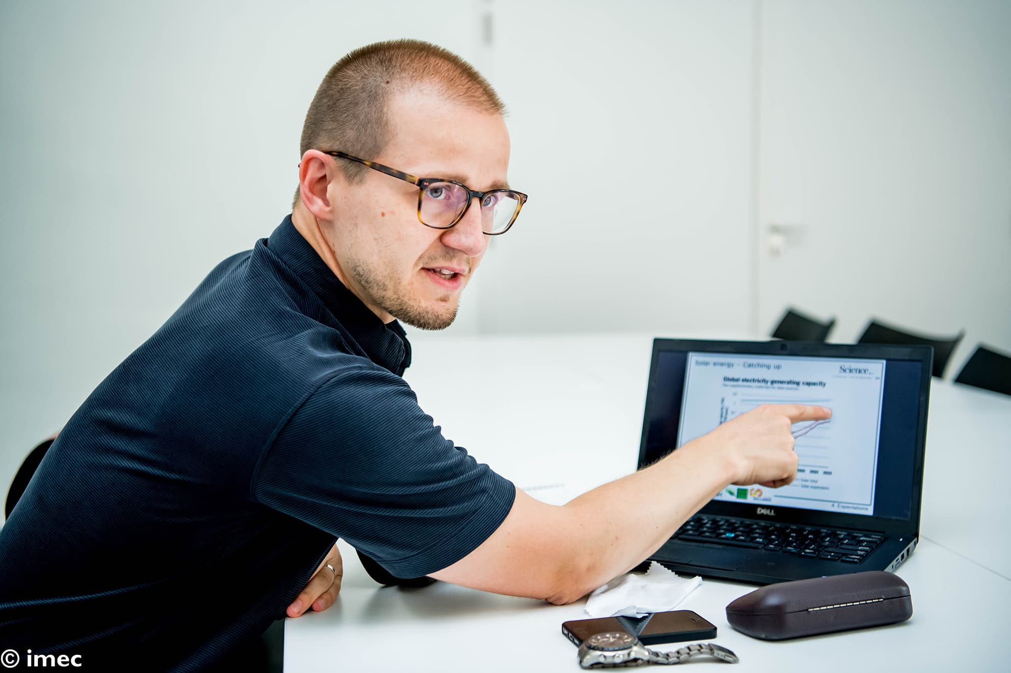 bart_vermang_01_0 Onderzoeker wijst naar een laptopscherm met een zonne-energiegrafiek in een vergaderruimte van het laboratorium.