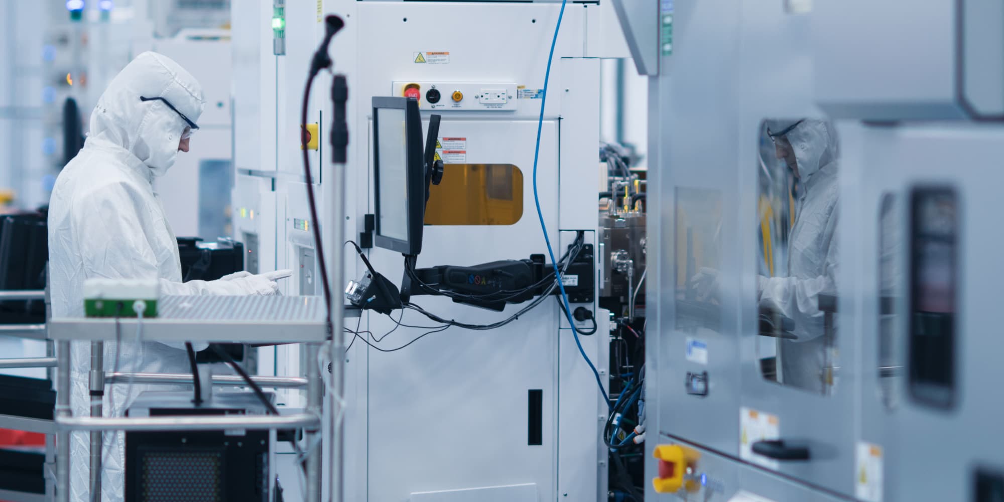 BEOL-nano-interconnects Two researchers in cleanroom suits working beside semiconductor processing equipment in a lab