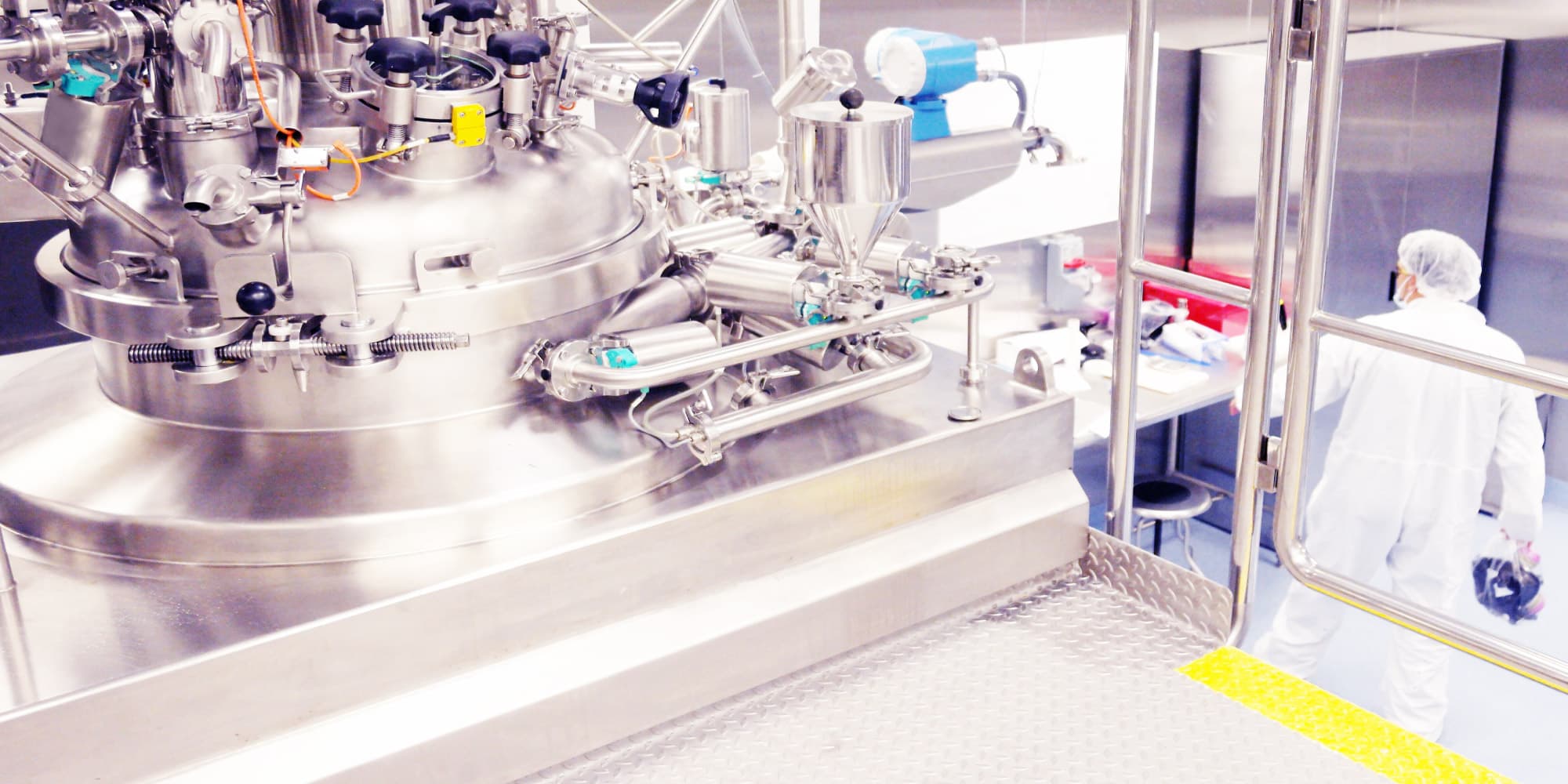 bioprocessing_1 Cleanroom bioprocessing equipment with stainless steel tanks and a researcher in protective clothing