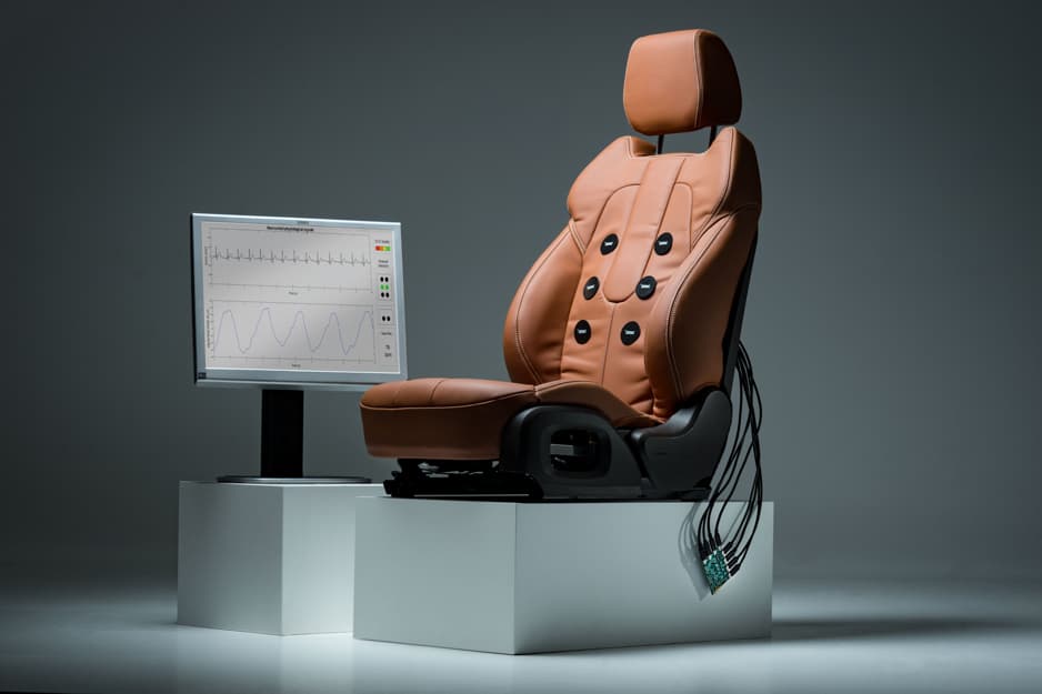 car-seat_capacitive_sensors_imec_RS4_0 Car seat fitted with capacitive sensors beside a monitor showing breathing and ECG traces