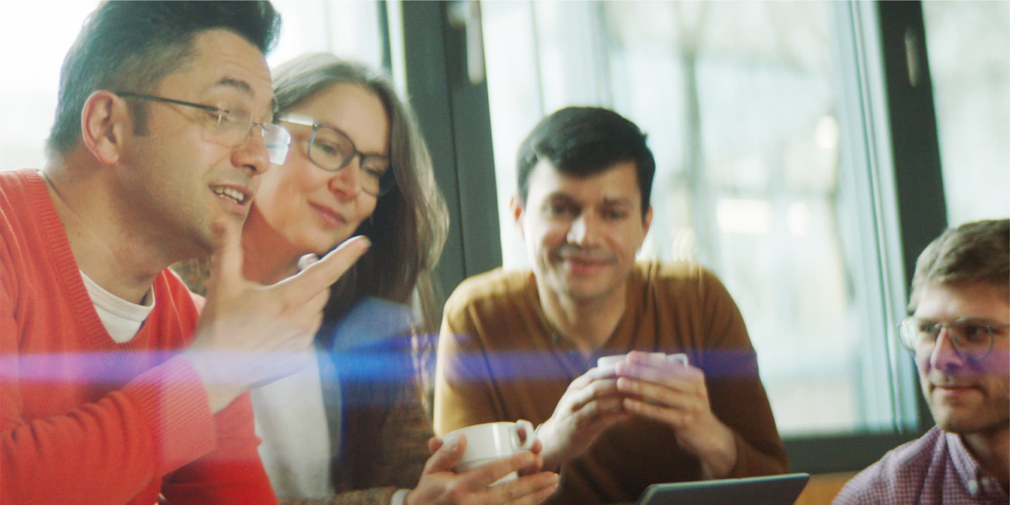 Career Four researchers in a casual meeting, talking and holding coffee cups