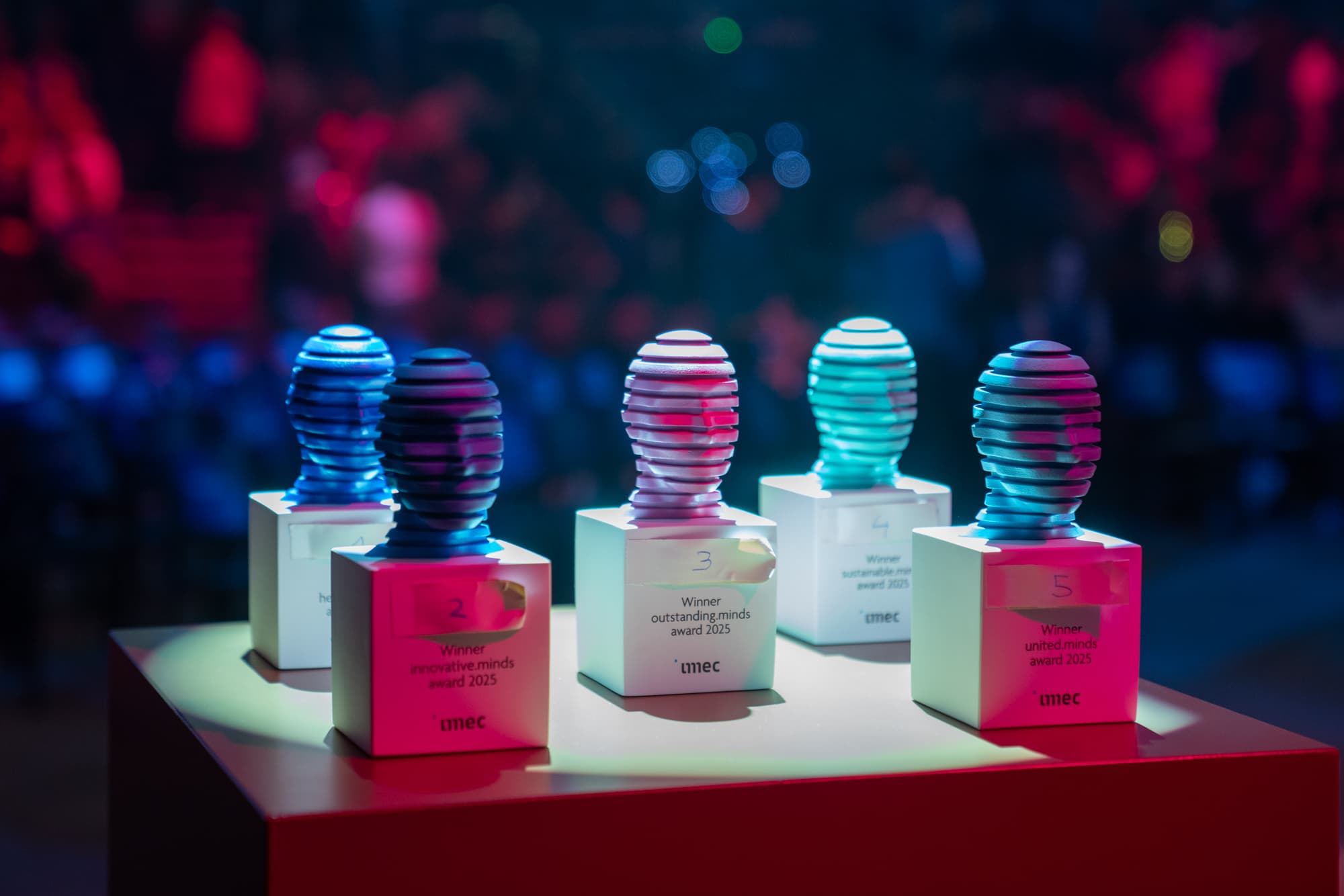 Carroussel%207 Award trophies with colorful stacked tops on lit pedestals at an event
