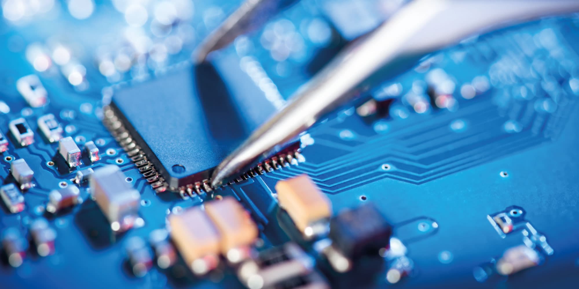 chip-visual Close-up of a microchip on a circuit board being handled with tweezers