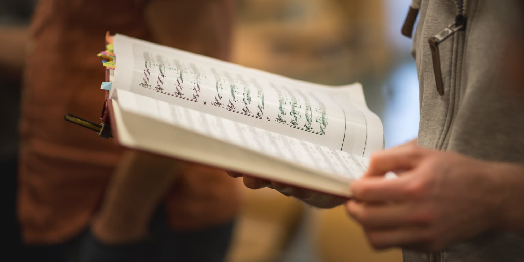 choirbox Close-up van een persoon die een koorpartij vasthoudt met kleurgecodeerde tabs, gebruikt om koorpartijen te repeteren
