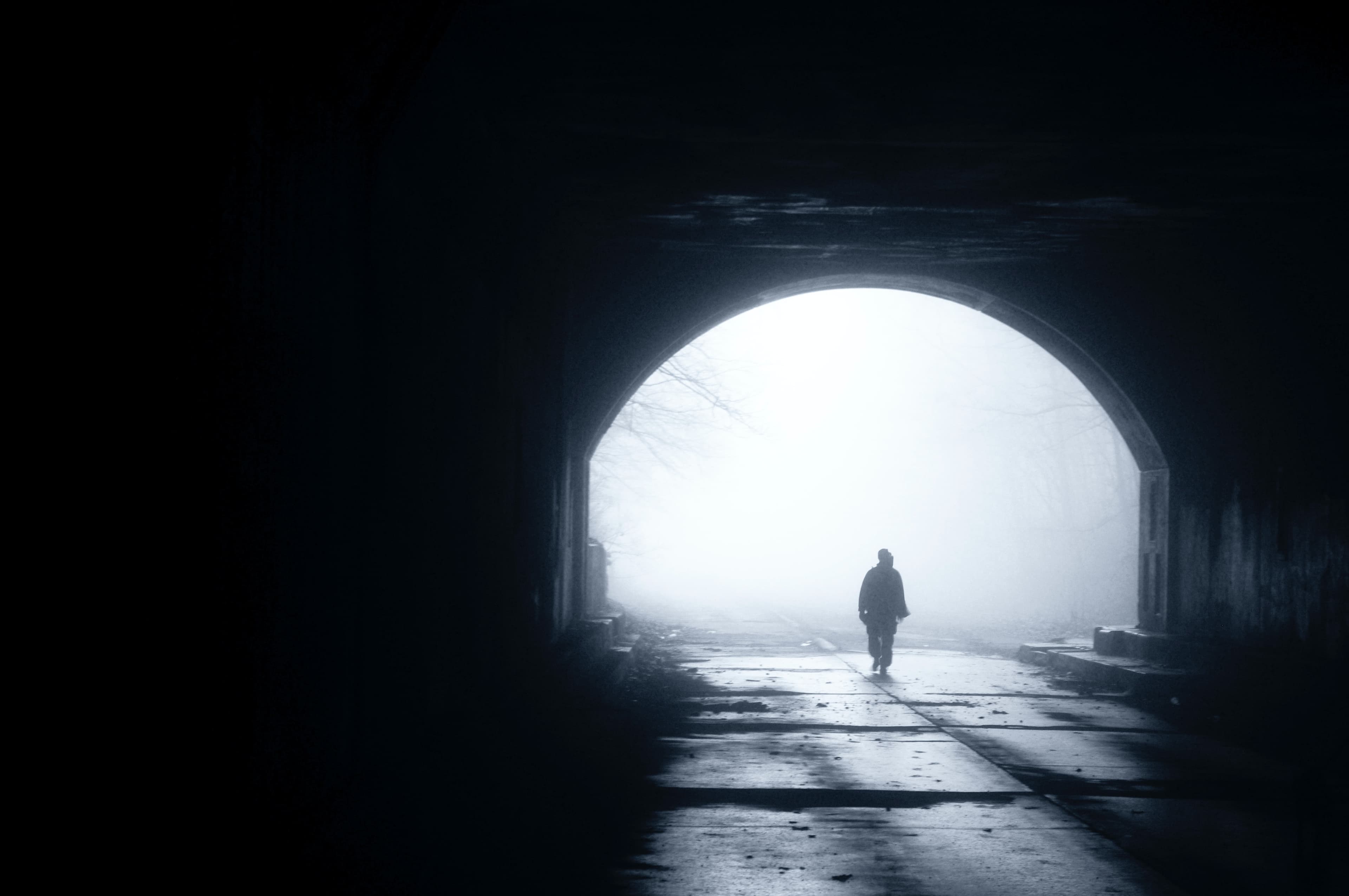 chris-buckwald-RXWgx93tz8w-unsplash Silhouet van een persoon die door een mistige tunnel naar de heldere uitgang loopt