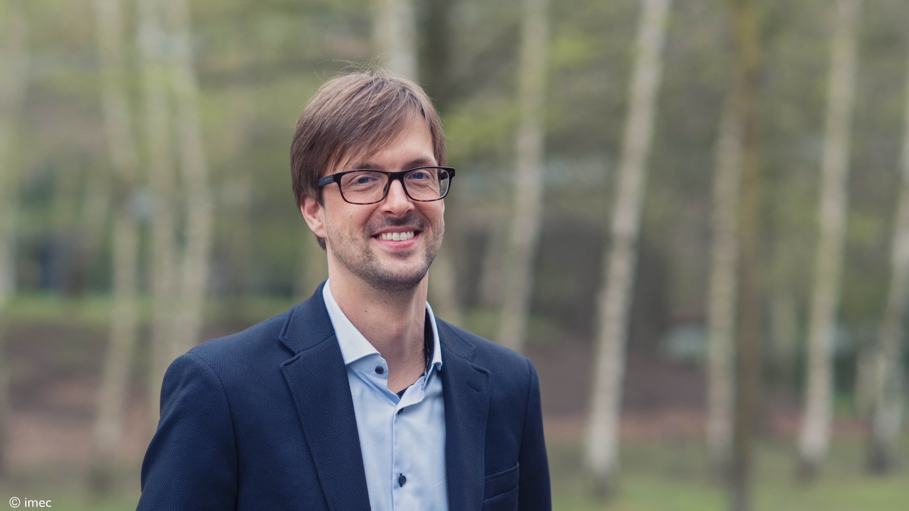 Christian%20Bachman Portrait of Christian Bachmann smiling outdoors in a dark blazer and glasses.