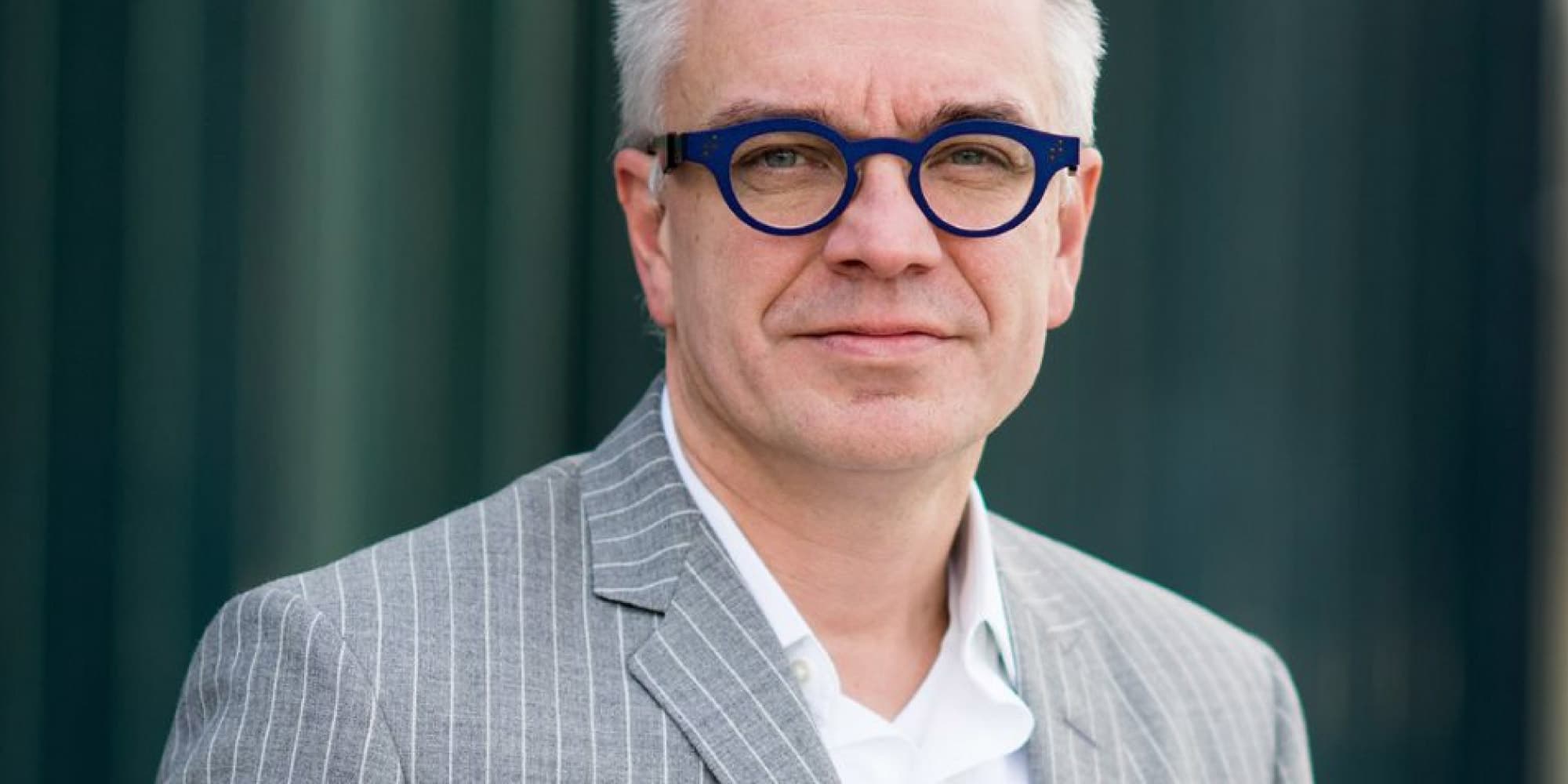 chrisvanhoof Portrait of imec fellow Chris Van Hoof wearing blue glasses and a gray pinstriped suit.