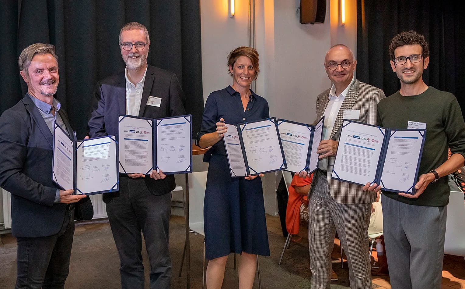 CJ6A1583 Vijf vertegenwoordigers houden ondertekende partnerschapsdocumenten vast tijdens een formele ceremonie.