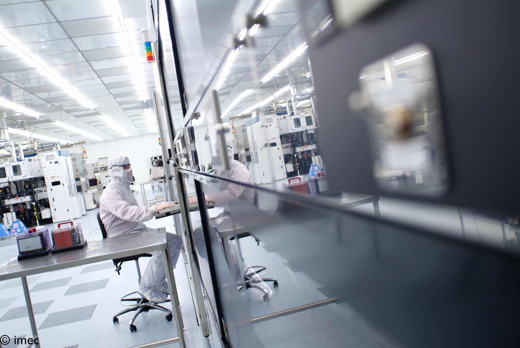 Cleanroom_19 Cleanroom researcher seated at a workstation beside semiconductor equipment