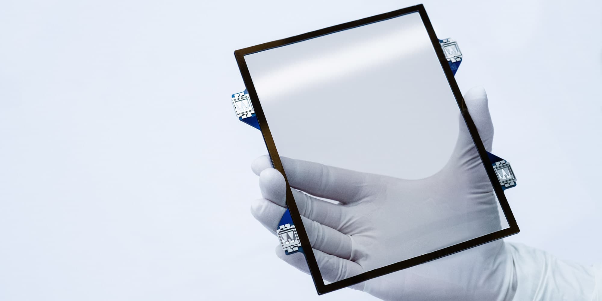 CNT Gehandschoende hand houdt een transparant vierkant pellicleframe van koolstofnanobuisjes met kleine bevestigingsclips