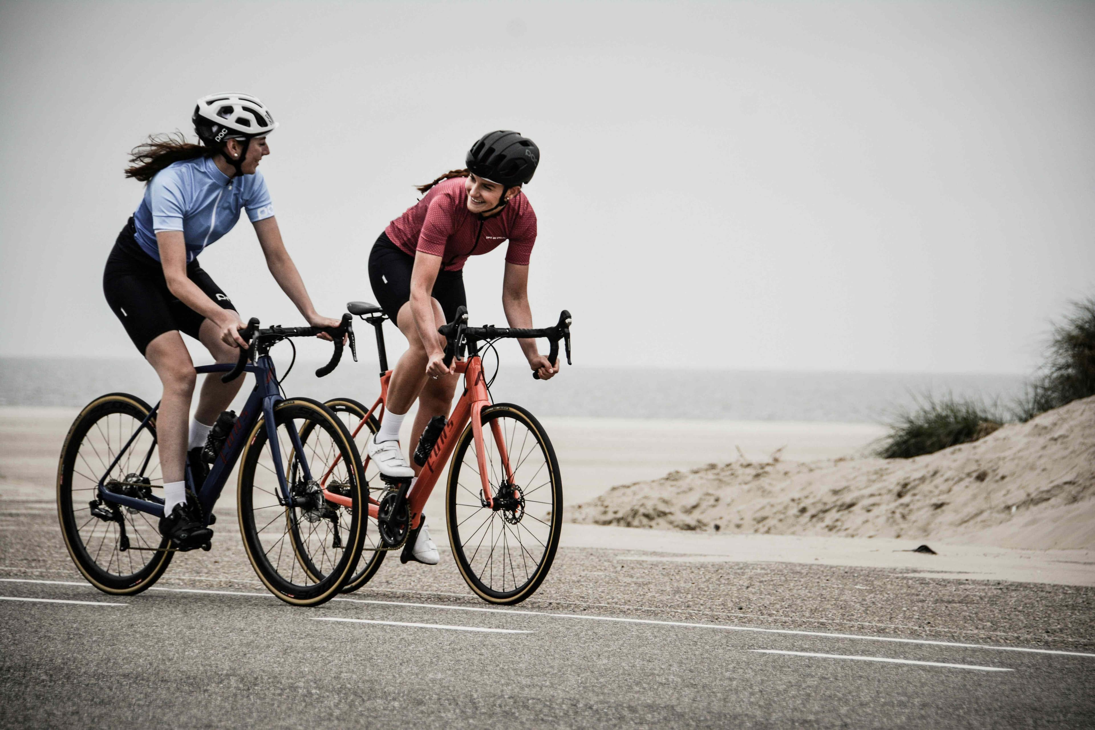 Two cyclists riding and chatting on coastal road Two cyclists riding road bikes and chatting on a coastal road