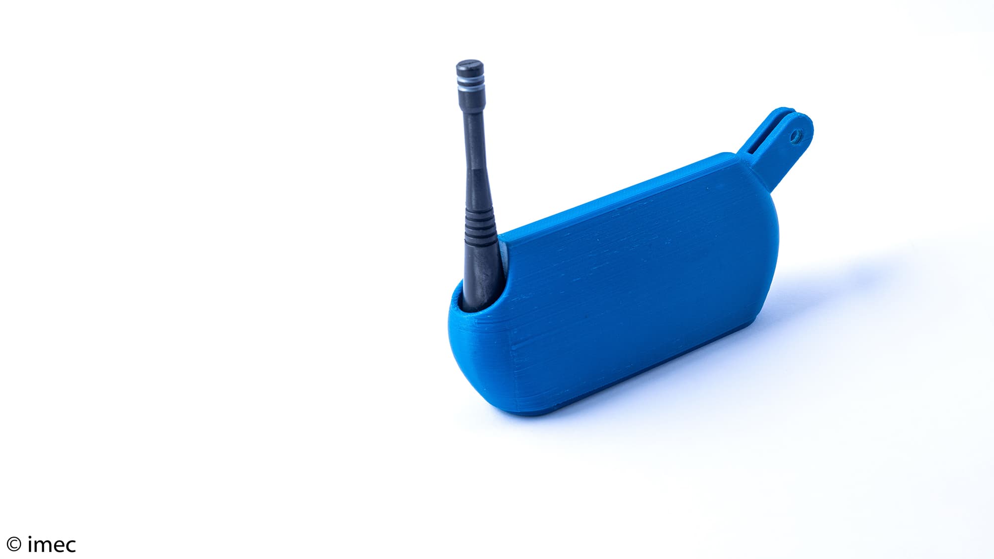 Conamo002 Blauwe 3D-geprinte apparaat houder met een zwarte antenne op een witte achtergrond