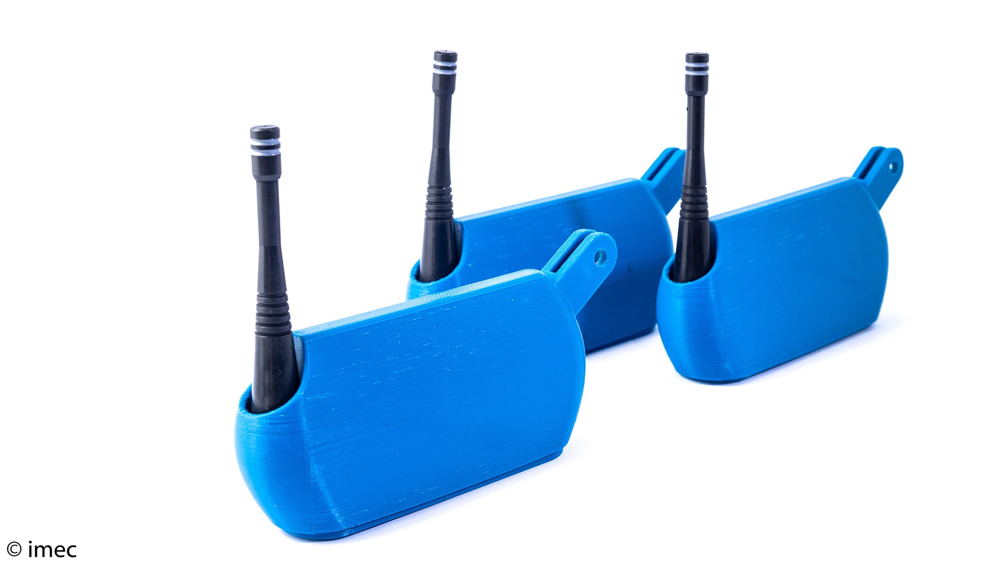Conamo003 Drie blauwe 3D-geprinte sensorbehuizingen met zwarte antennes op een witte achtergrond