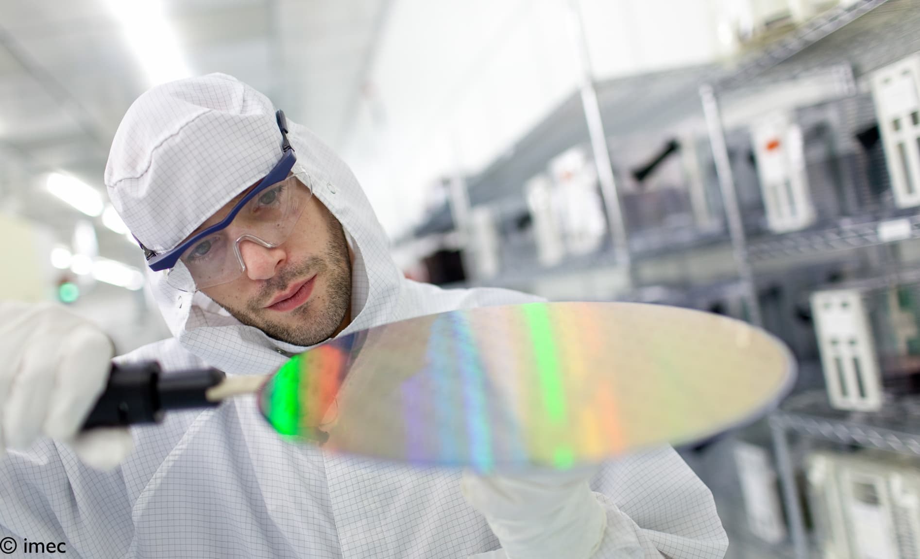 Custom%20wafer%20process Researcher in a cleanroom examining a reflective semiconductor wafer