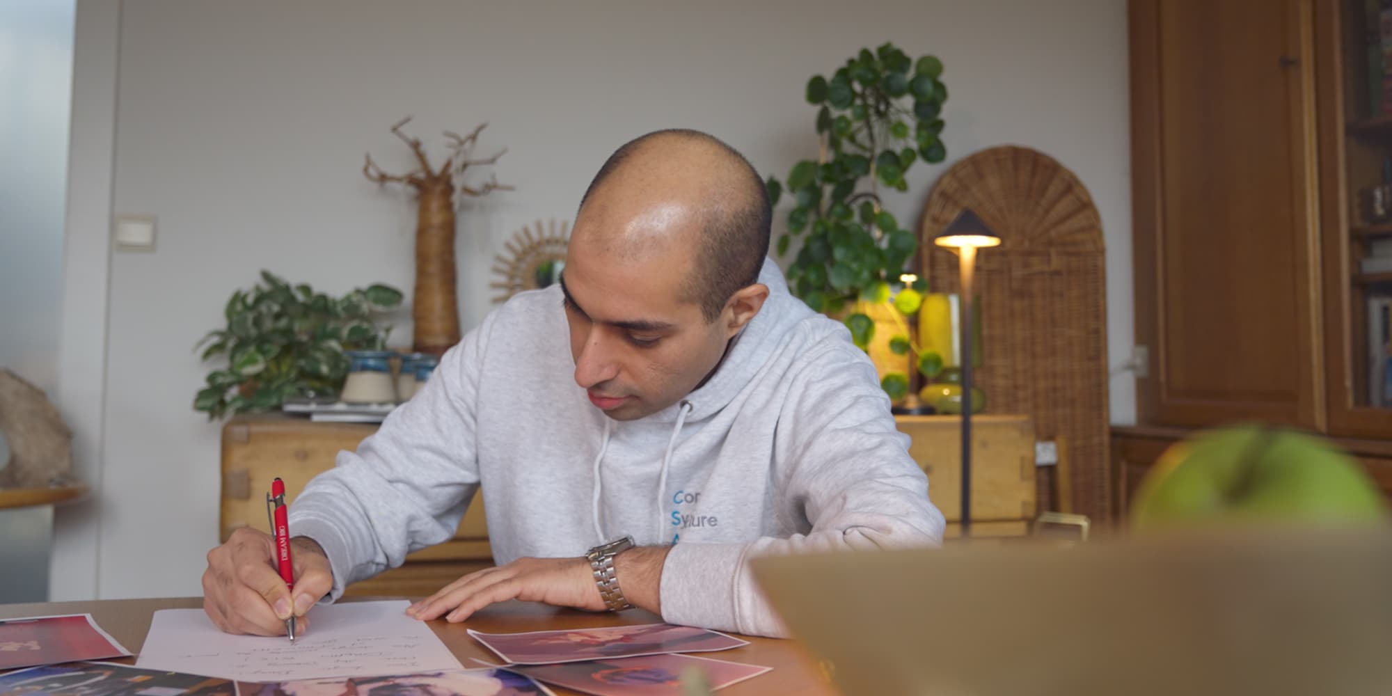 Darayus-Adil-Patel1 Darayus Adil Patel schrijft aan een tafel en kijkt naar papieren in een thuiskantoor.